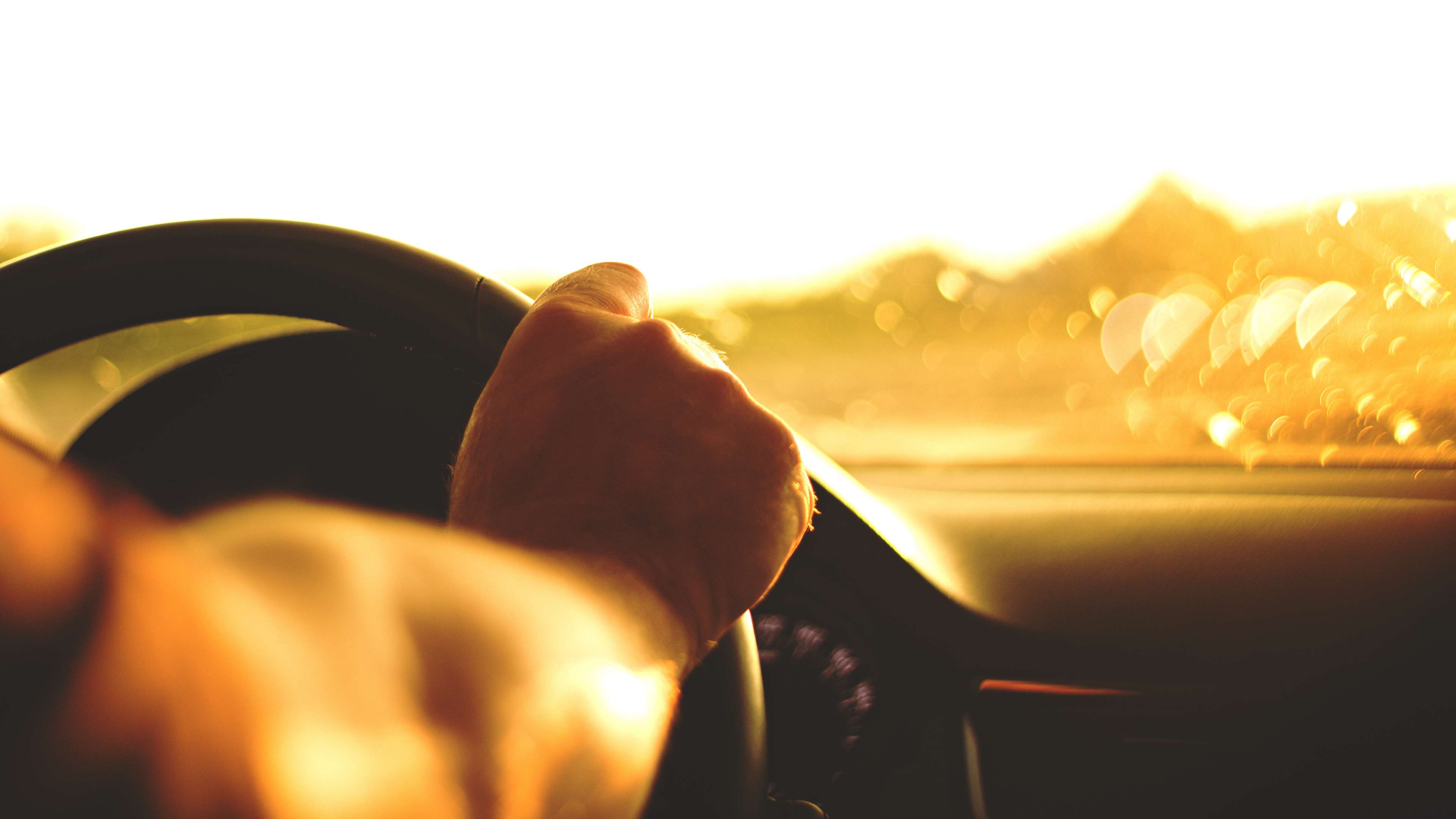 Hand on steering wheel during sunset 4K HD Wallpaper