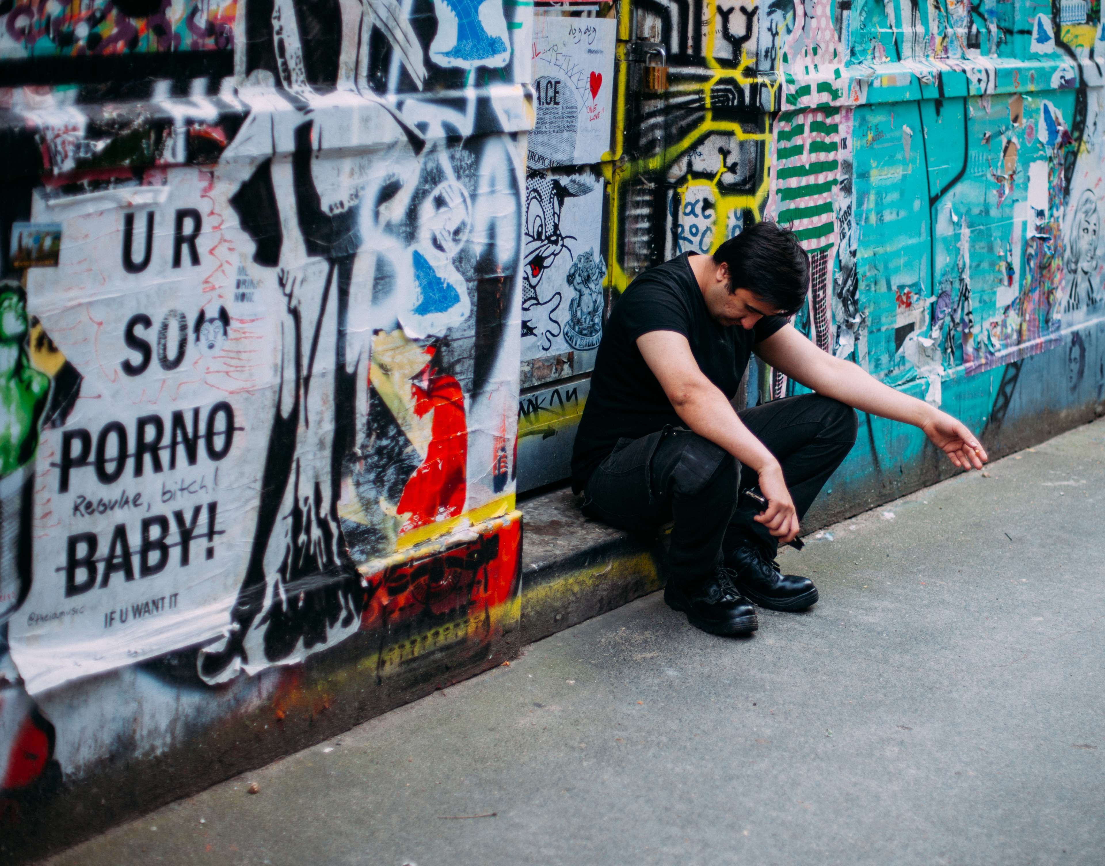 Man sitting by graffiti wall HD Wallpaper