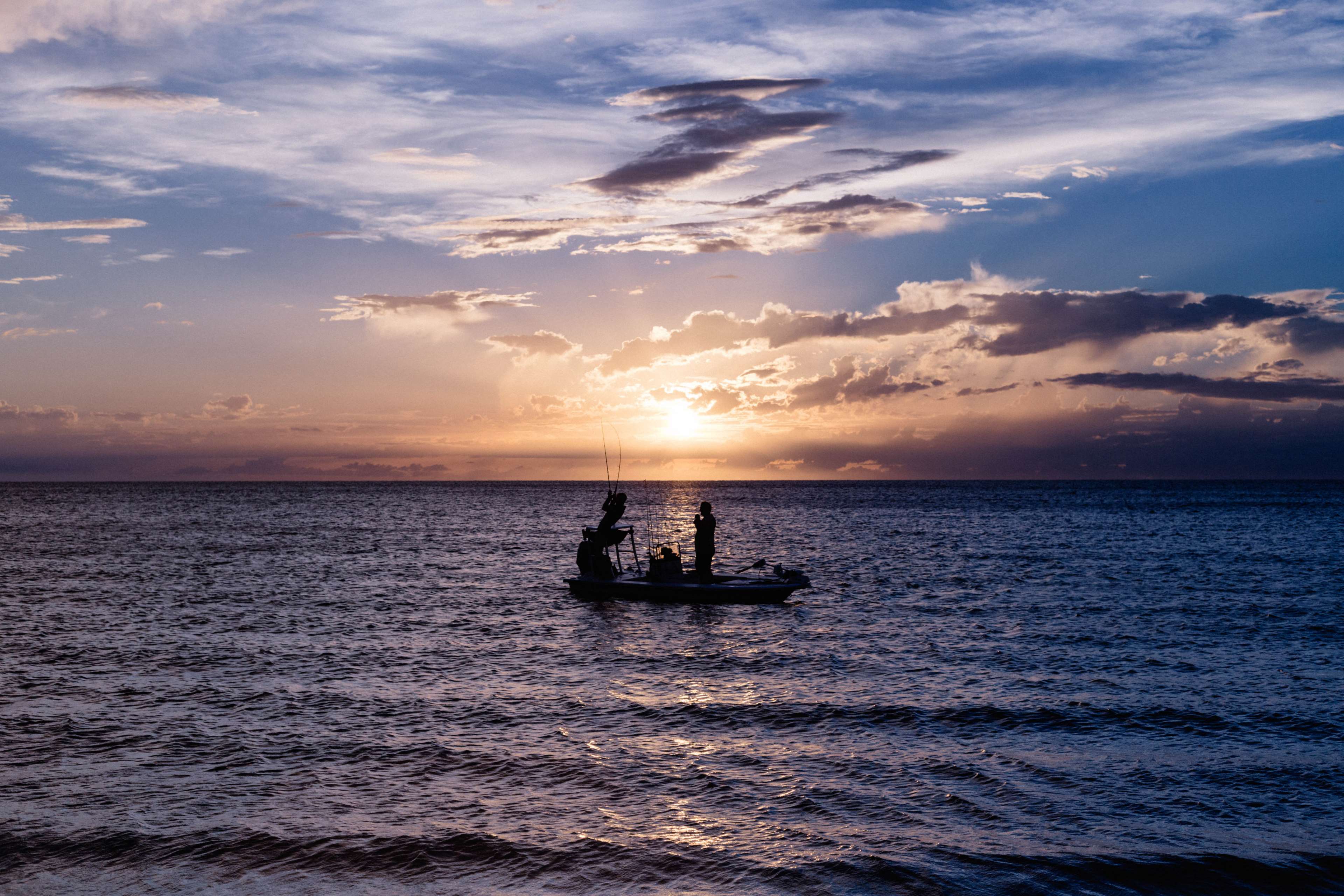 Two people fishing from a boat at sunset HD Wallpaper