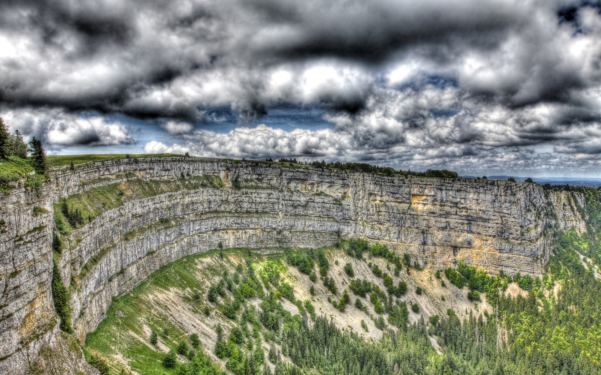 Panoramic view of a dramatic cliff face with stormy clouds HD Wallpaper