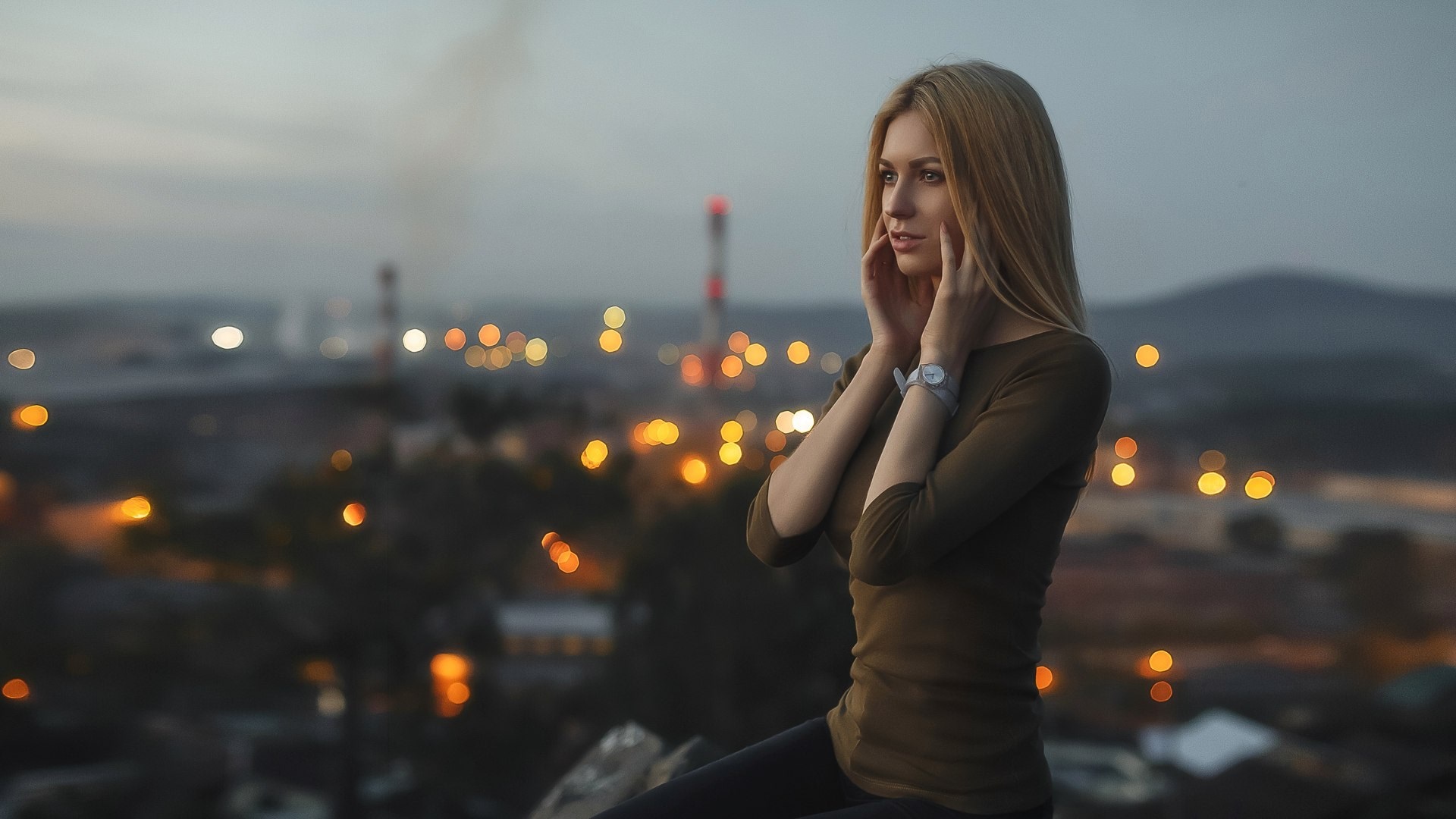 Woman with hands on face overlooking city lights HD Wallpaper