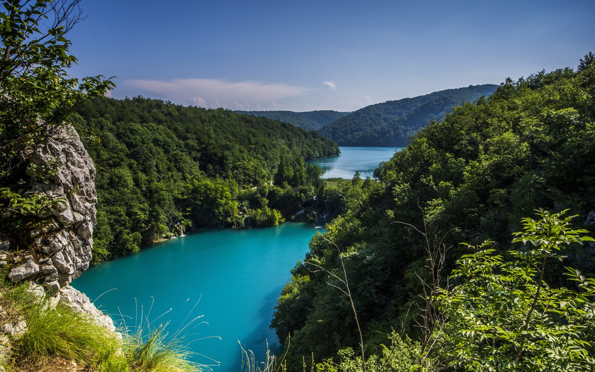 Turquoise lake surrounded by green forest and rocky cliffs HD Wallpaper