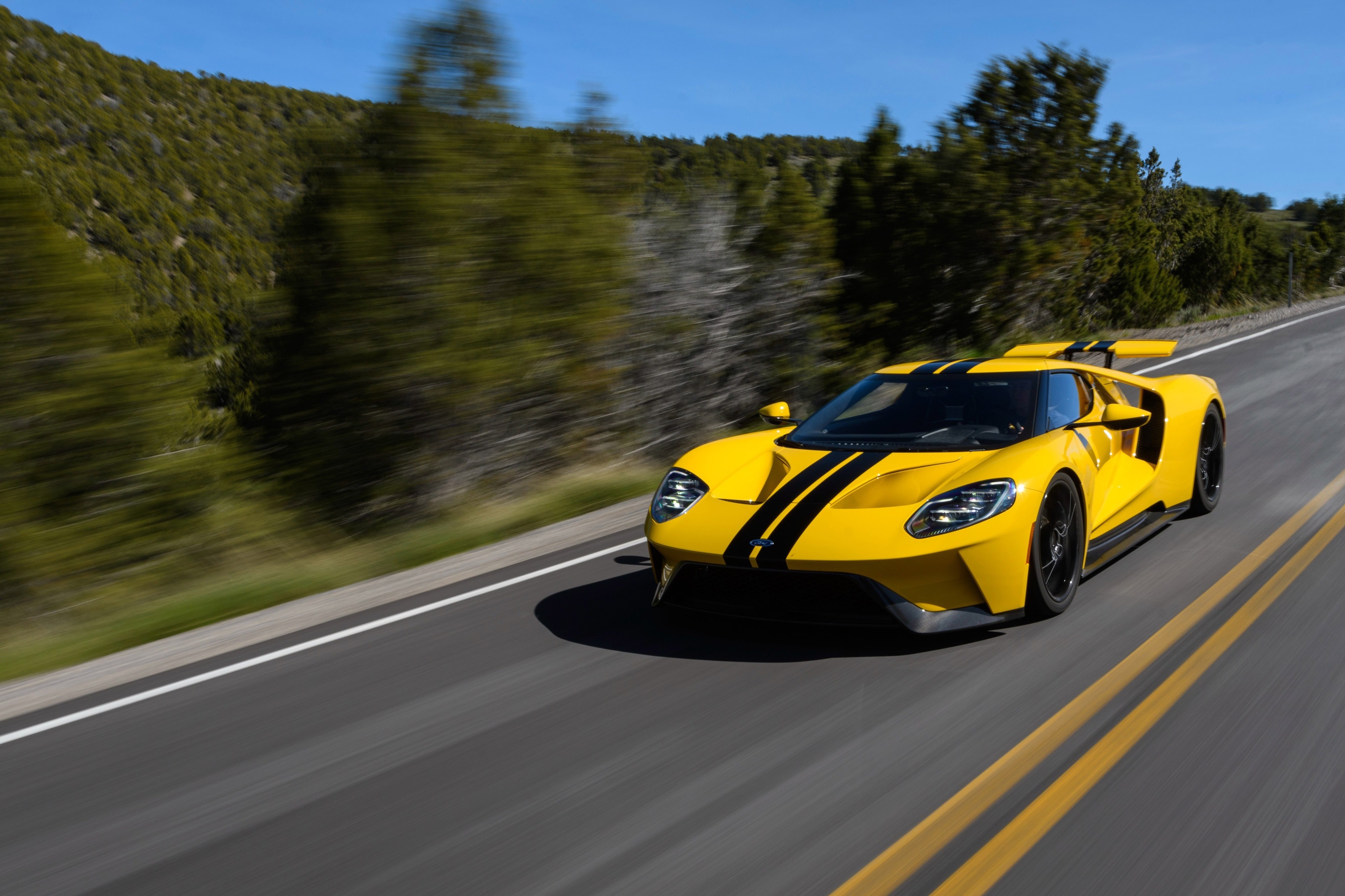 Yellow Ford GT with black stripes on a road HD Wallpaper