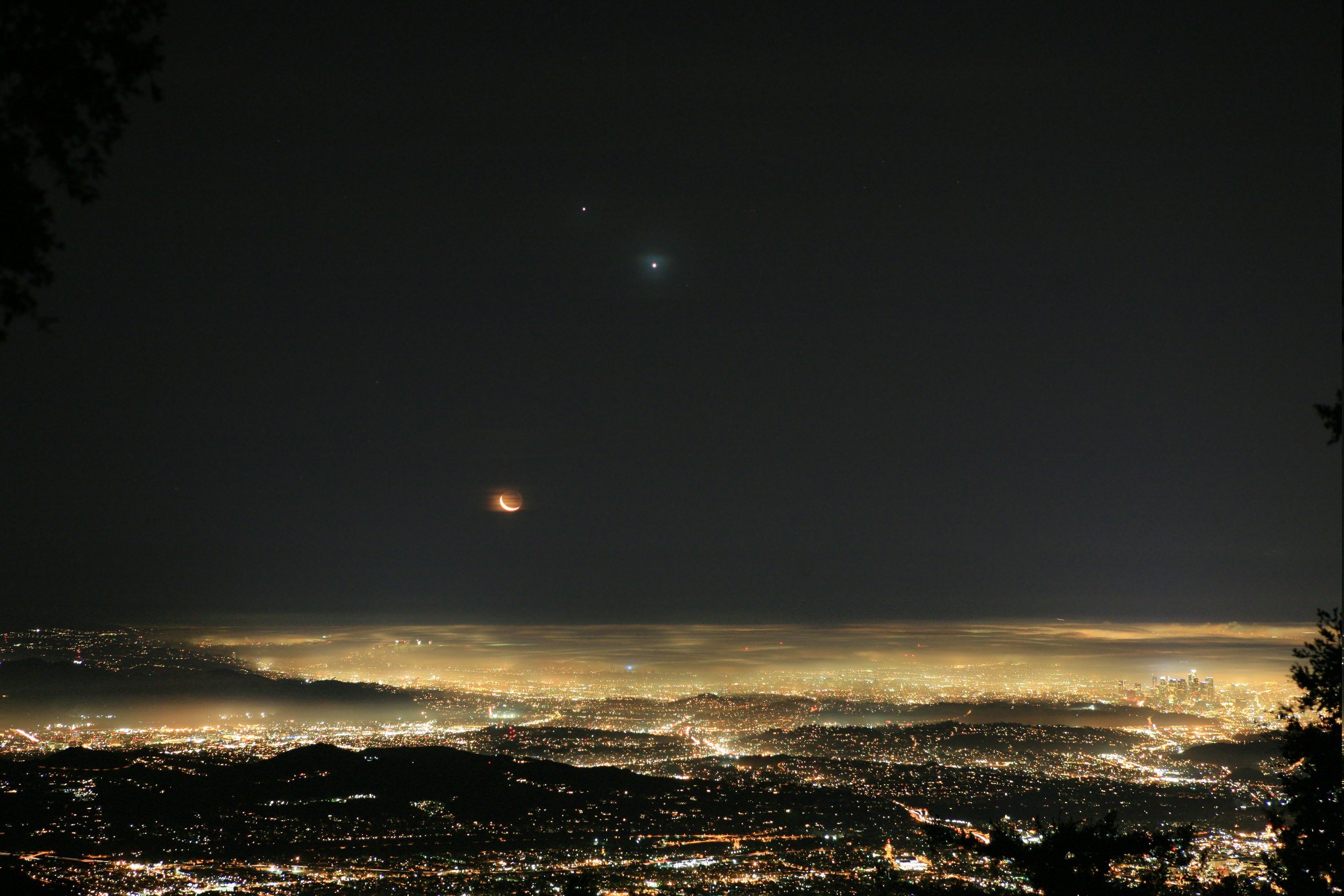 Lunar eclipse over a misty city at night with Venus and Jupiter HD Wallpaper