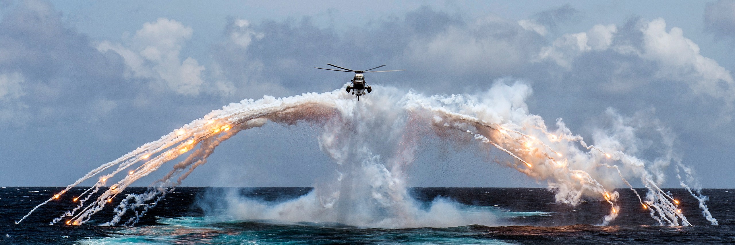 Sikorsky CH-124 Sea King helicopter deploys flares over the ocean HD Wallpaper