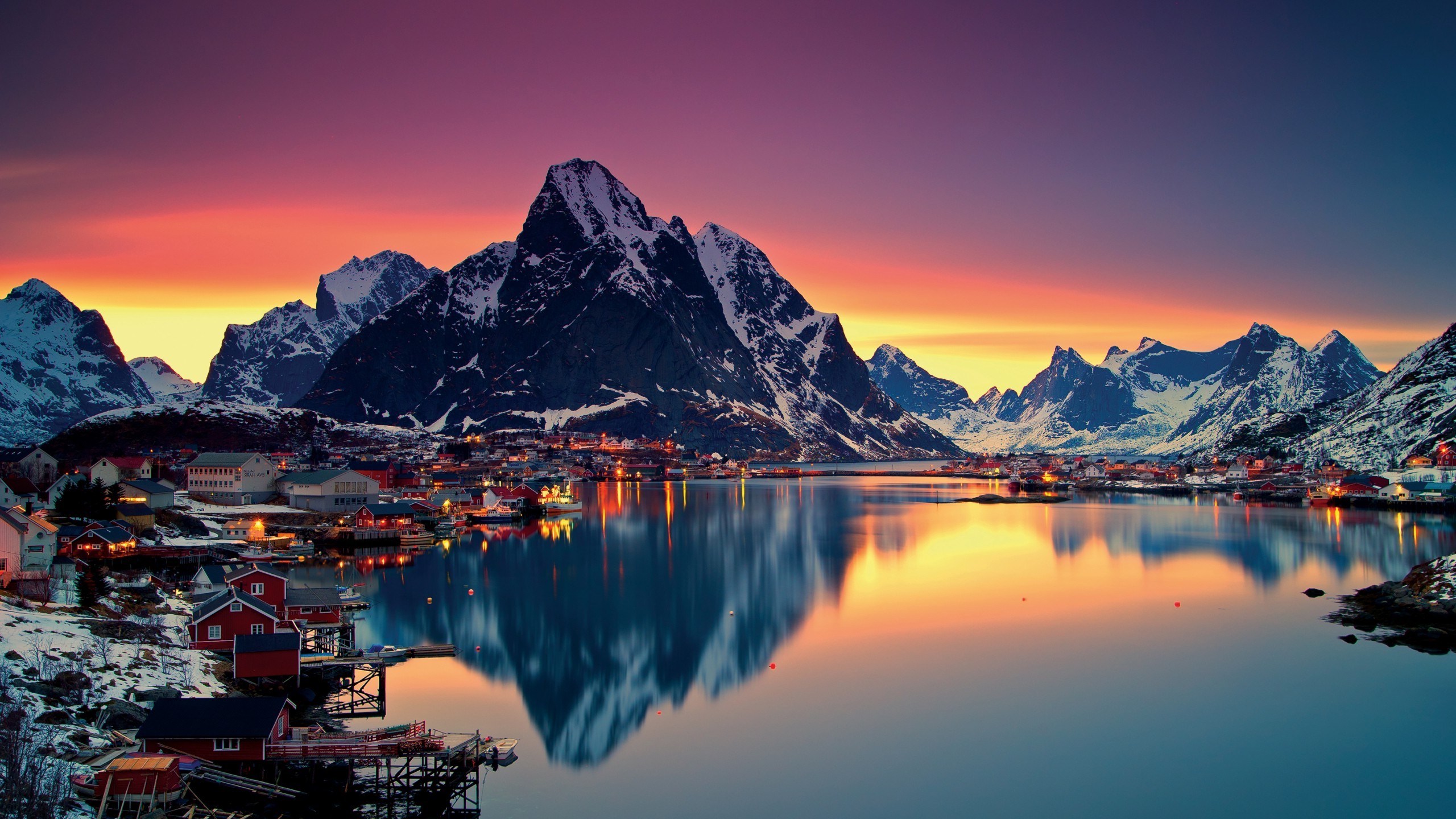 Village and mountains reflected in a lake at sunset HD Wallpaper