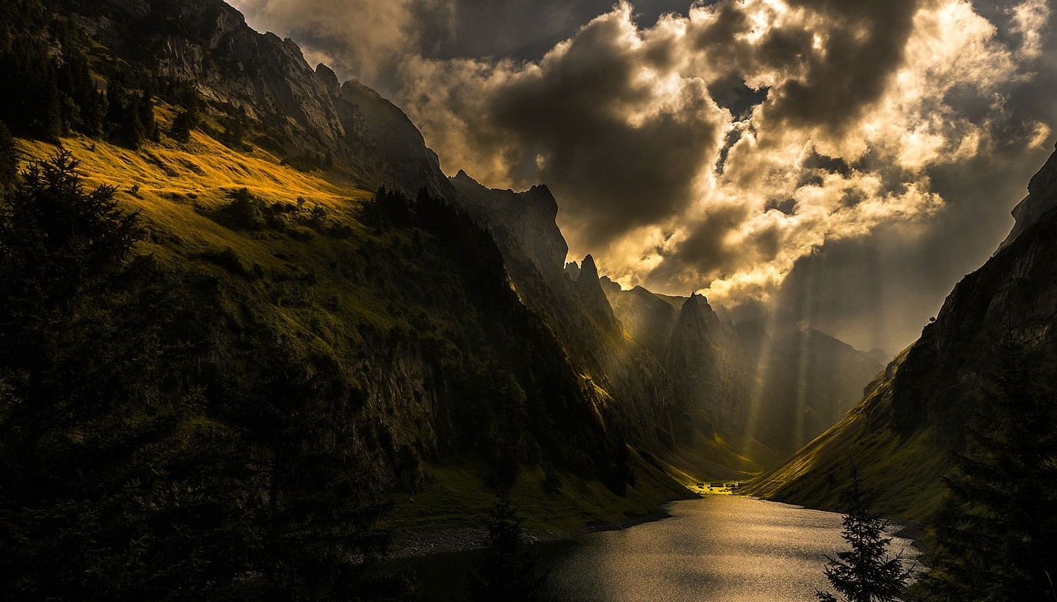 Sun rays over a mountain lake with dark clouds HD Wallpaper
