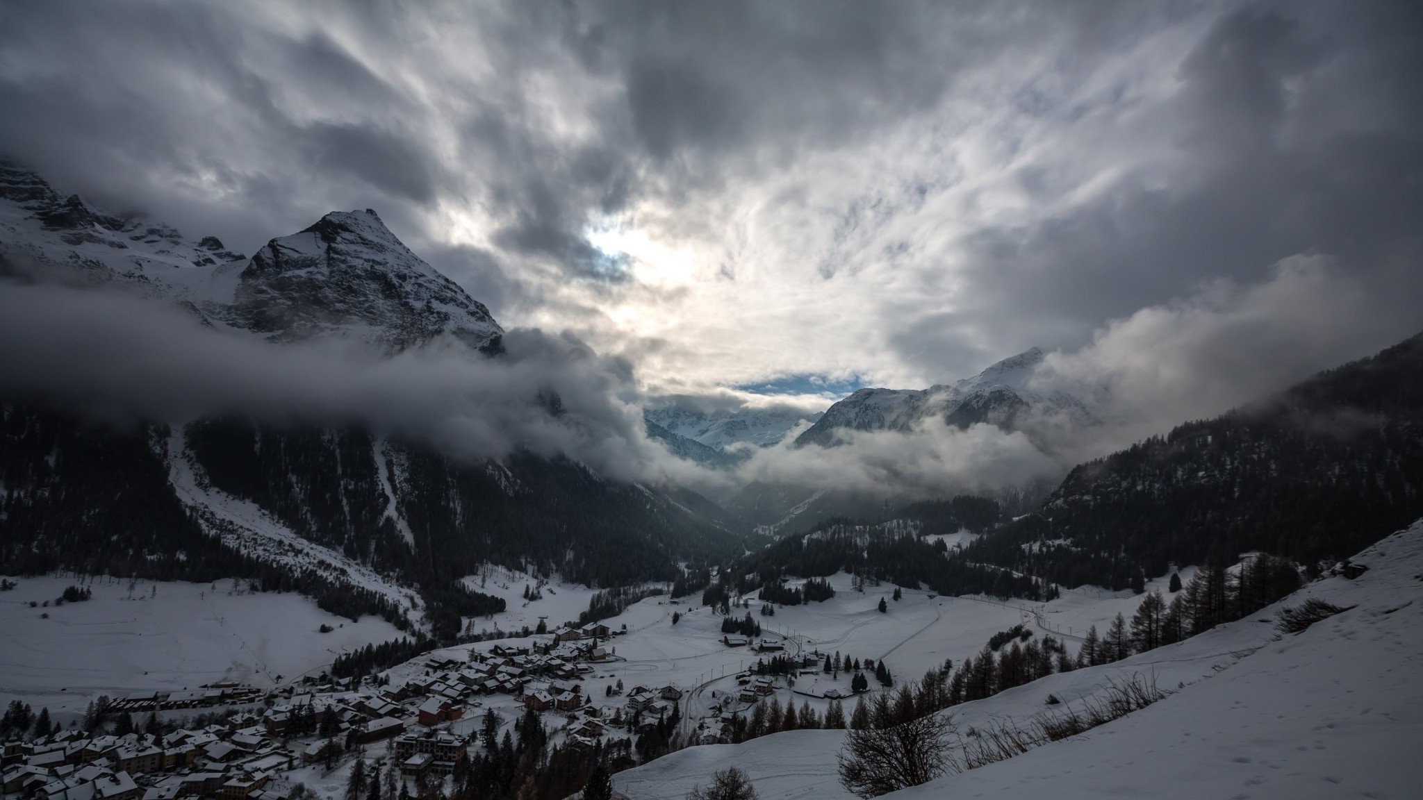 Snowy mountain valley with clouds and village HD Wallpaper