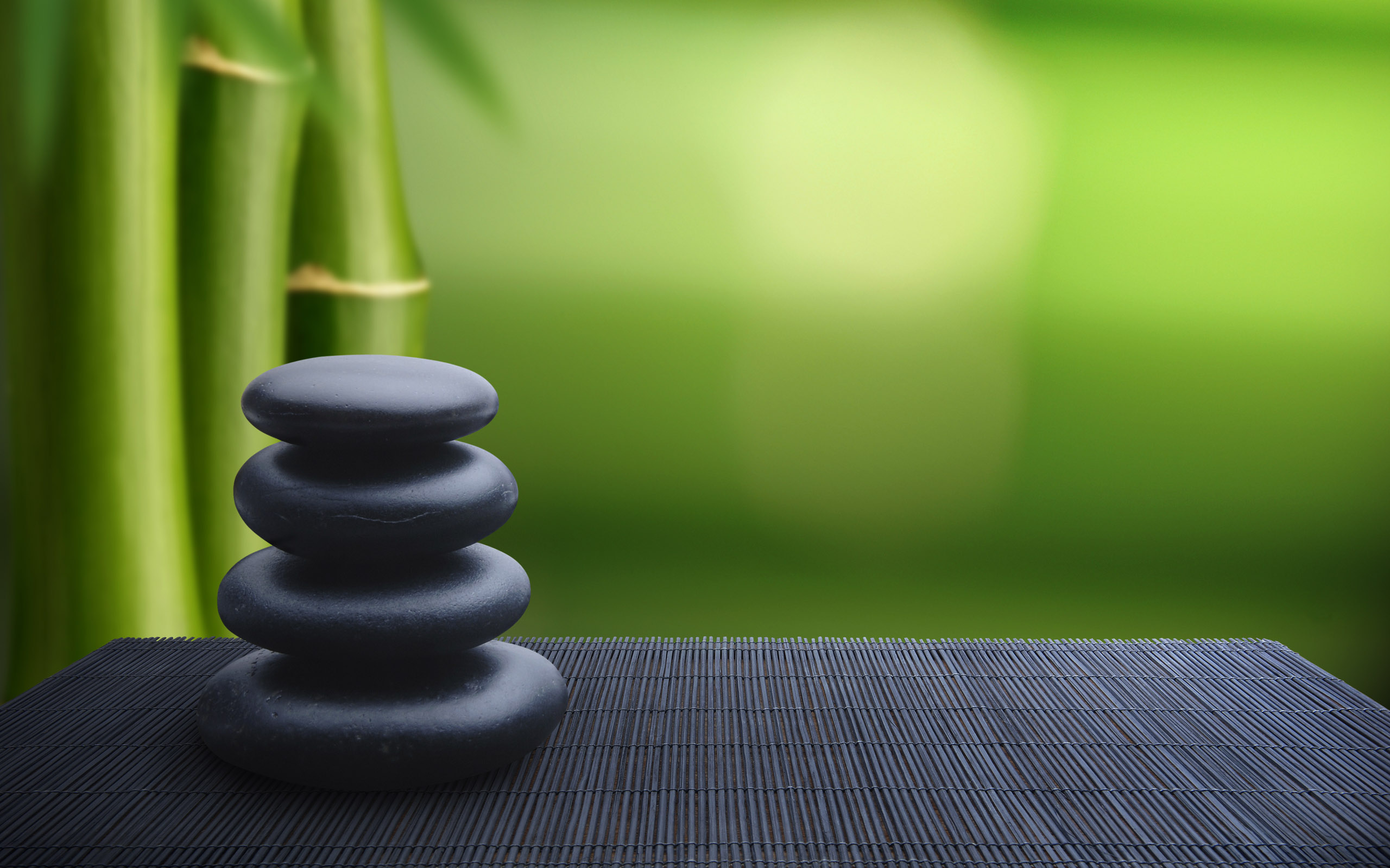 Stack of black stones with bamboo in background HD Wallpaper