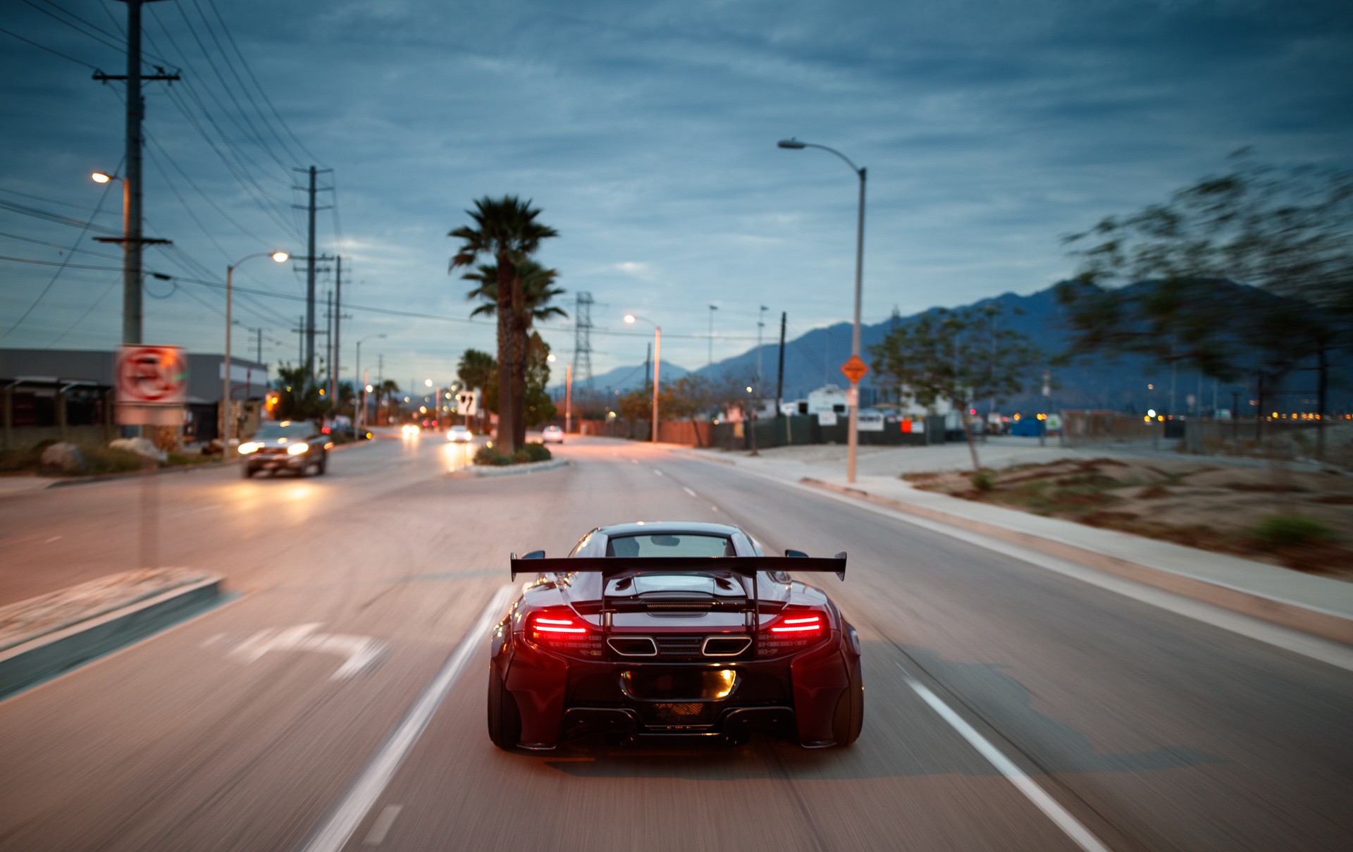 McLaren MP4-12C driving on a road at dusk HD Wallpaper
