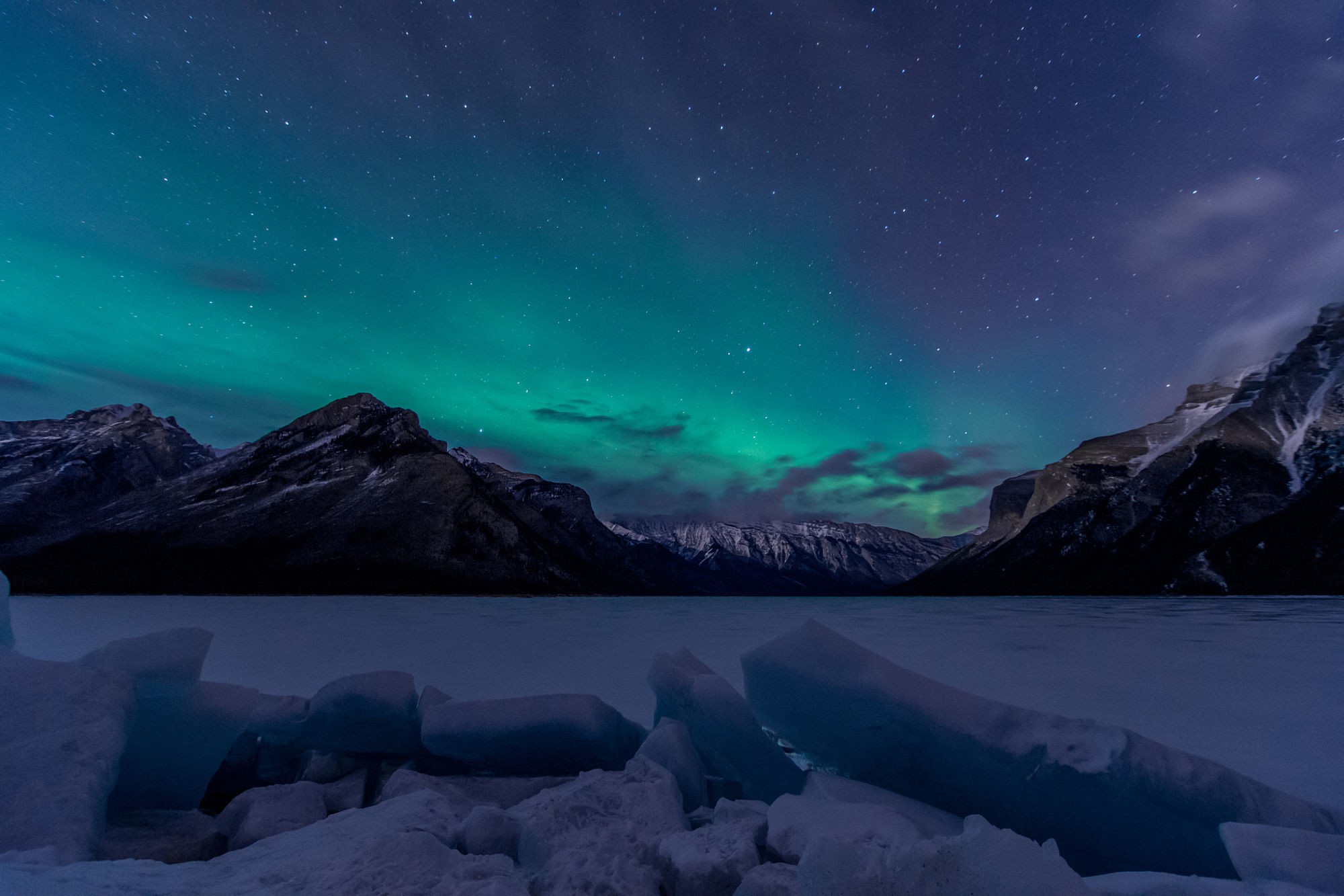 Aurora Borealis over snow-covered mountains and frozen lake HD Wallpaper