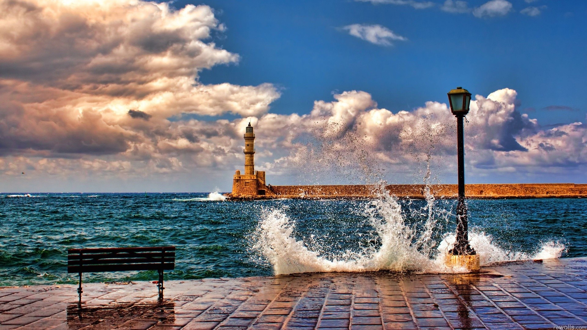 Waves crashing near a lighthouse and lamp post in Crete HD Wallpaper