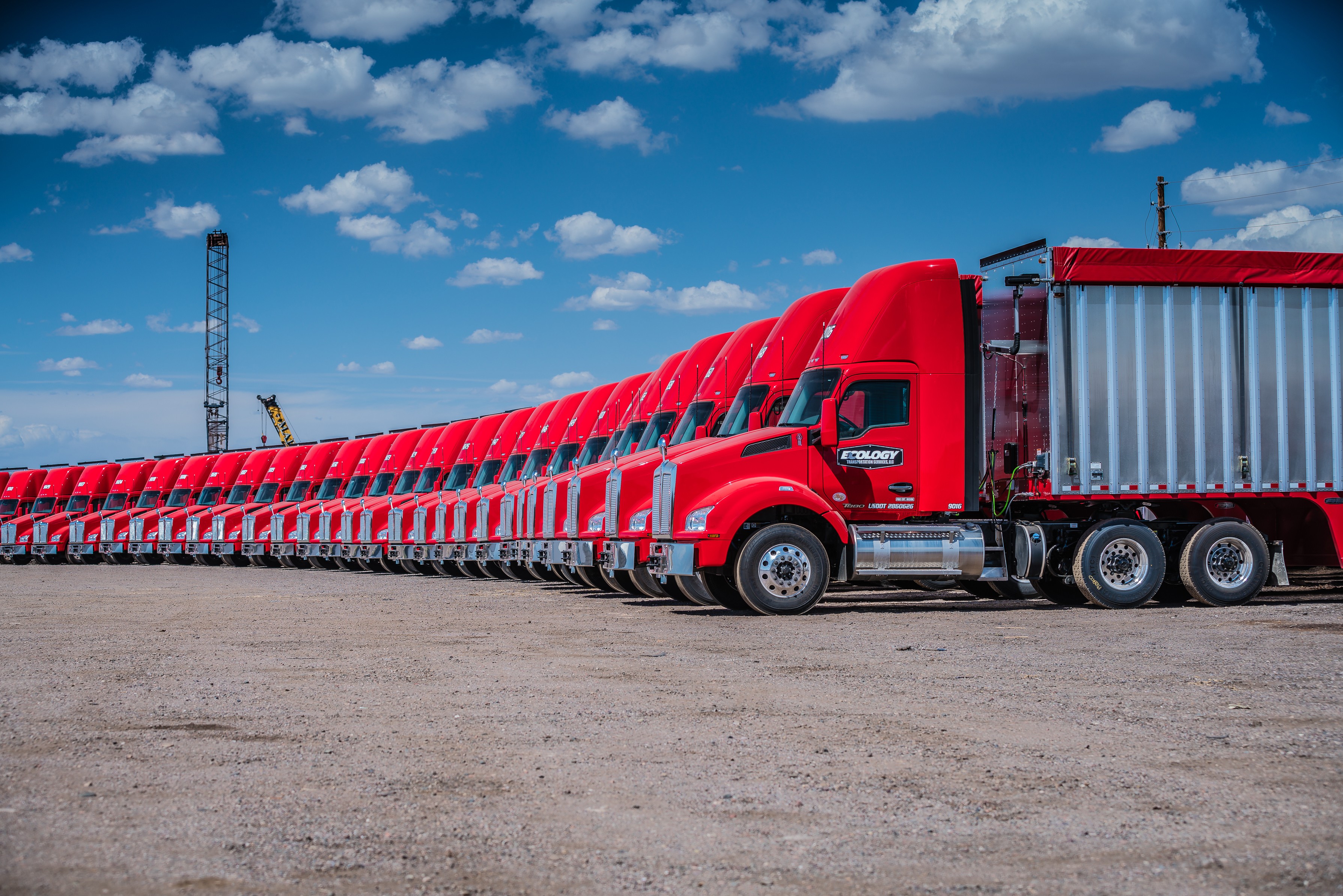 Line of red Ecology trucks parked on gravel lot HD Wallpaper