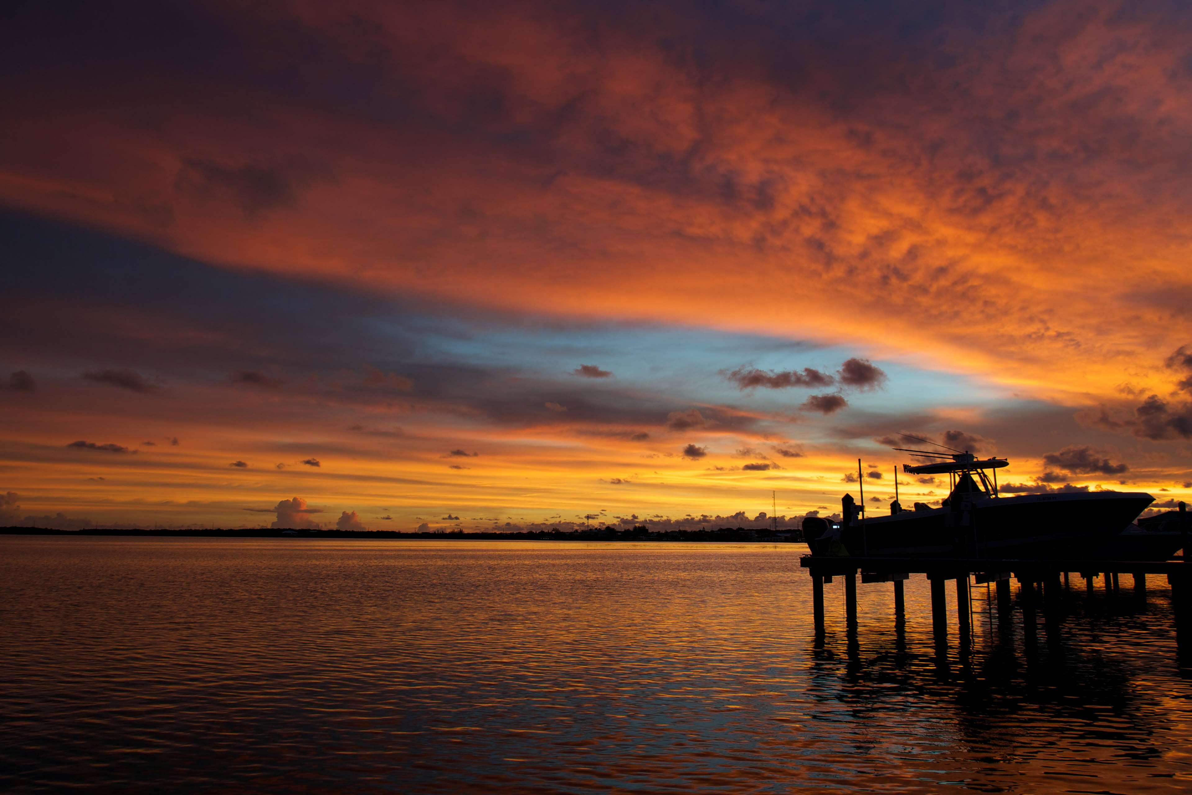 Colorful sunset over the ocean with a boat at the dock 4K HD Wallpaper