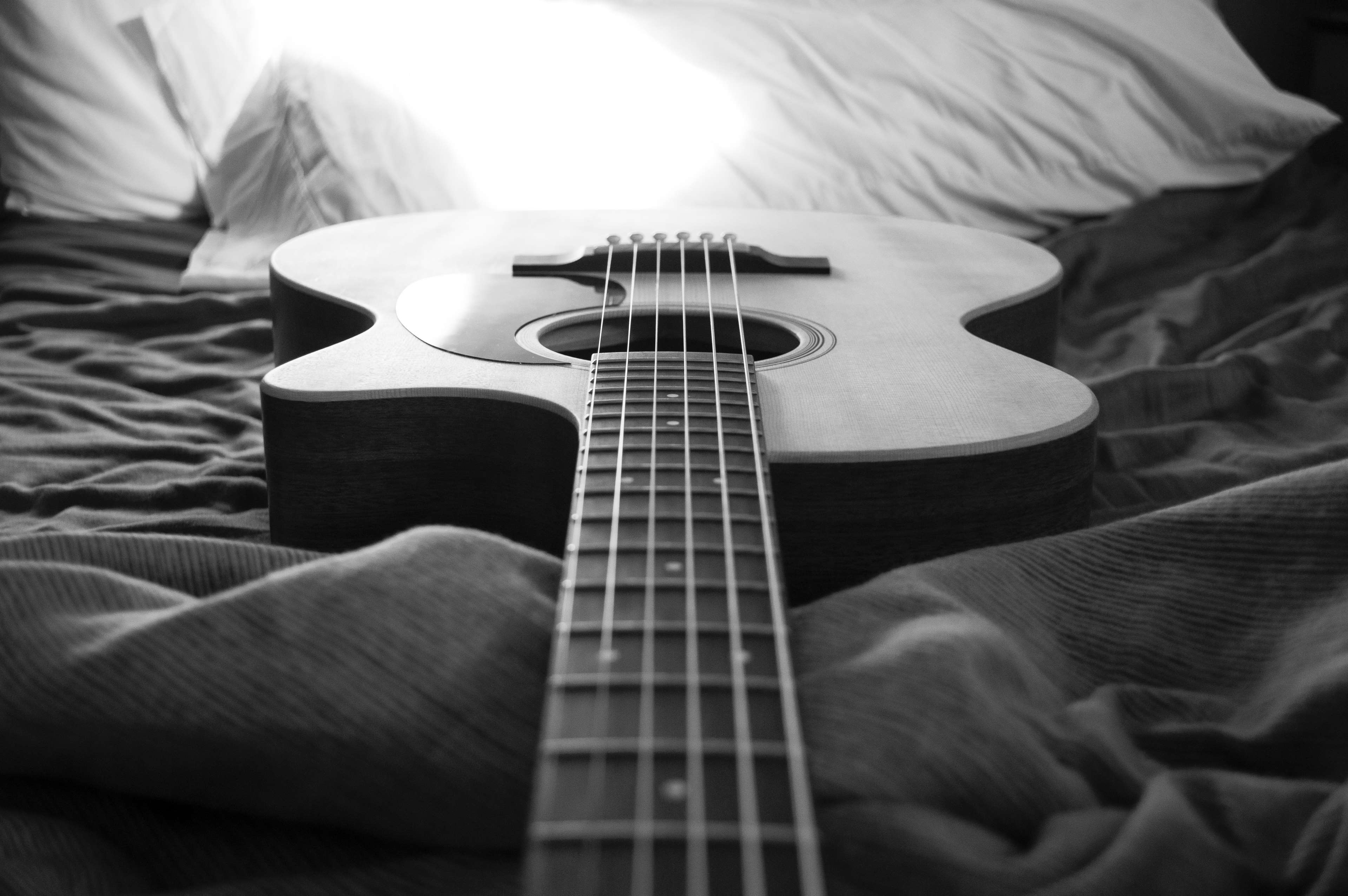 Acoustic guitar on a bed, black and white HD Wallpaper