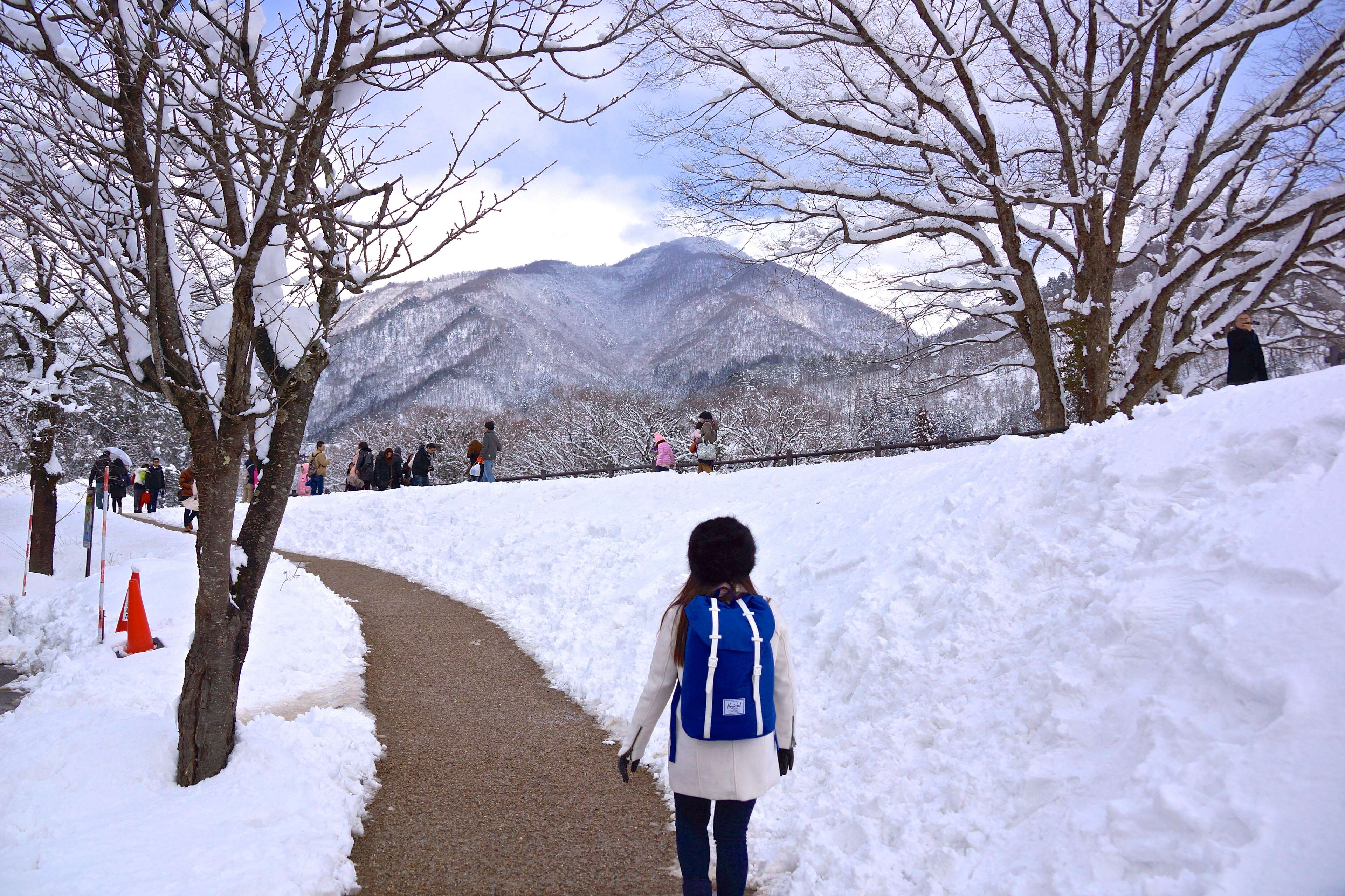 Girl with blue backpack in snowy landscape with mountains HD Wallpaper