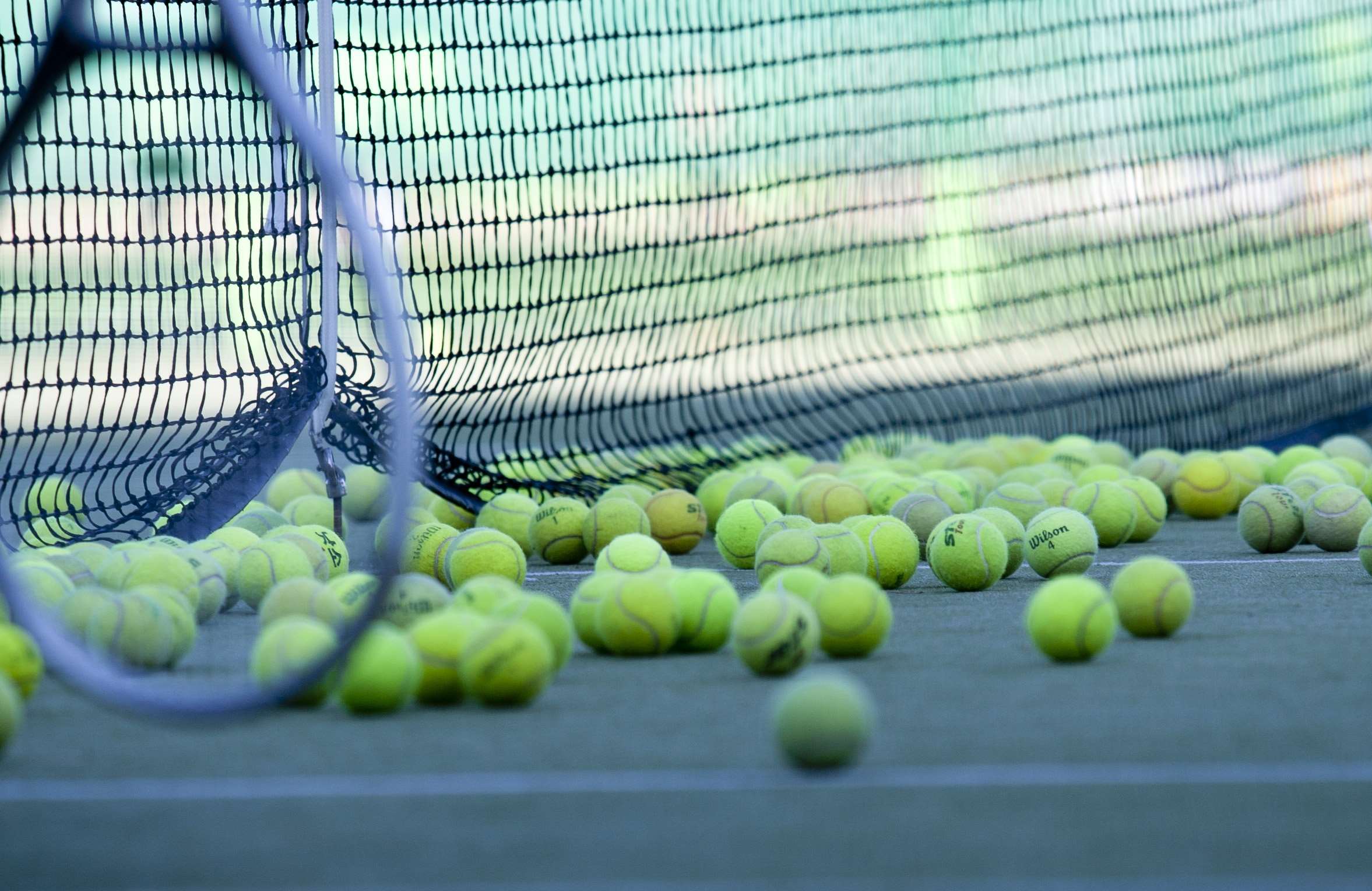 Tennis balls on a court near a net HD Wallpaper