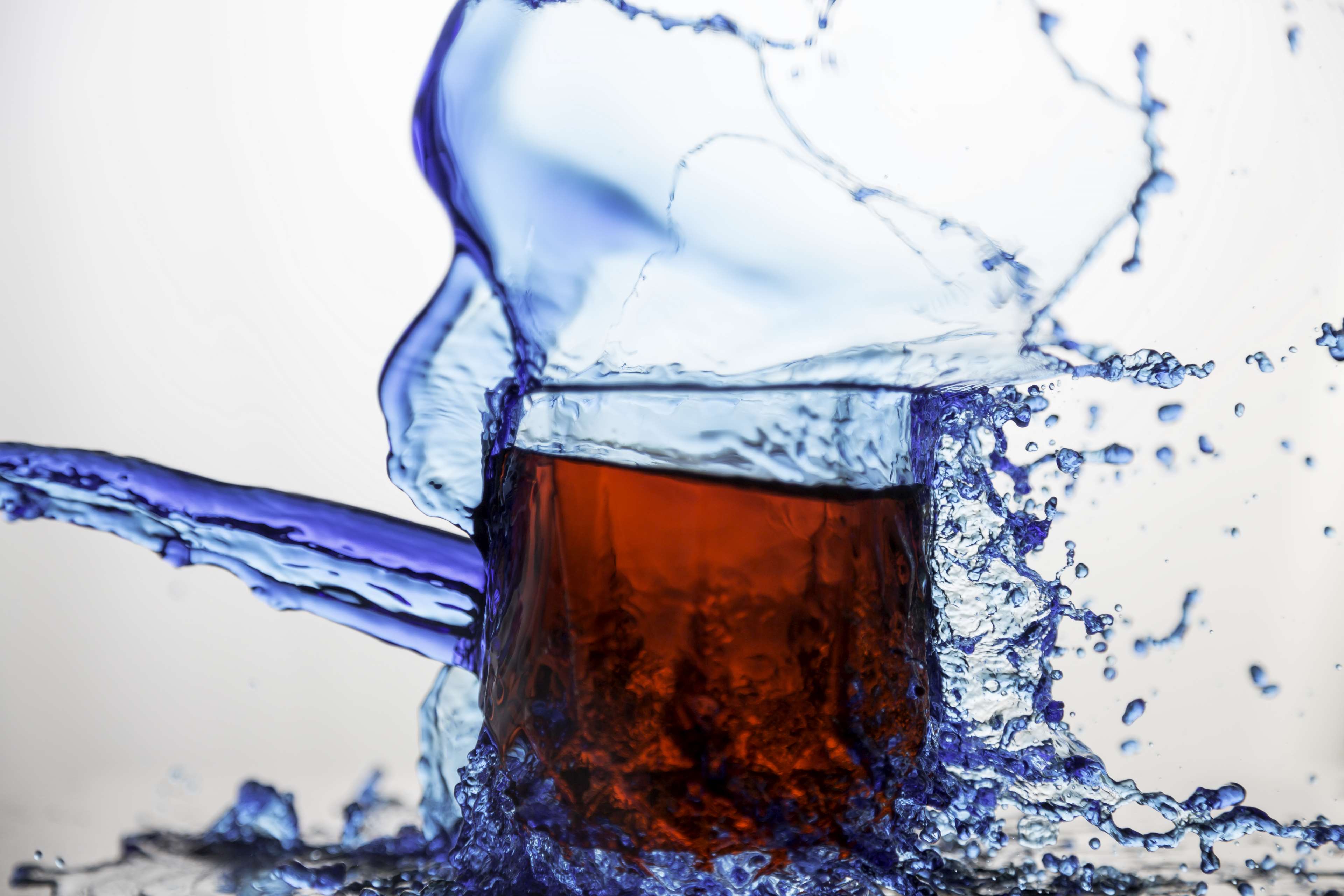 Blue liquid splashing out of a glass with red liquid HD Wallpaper