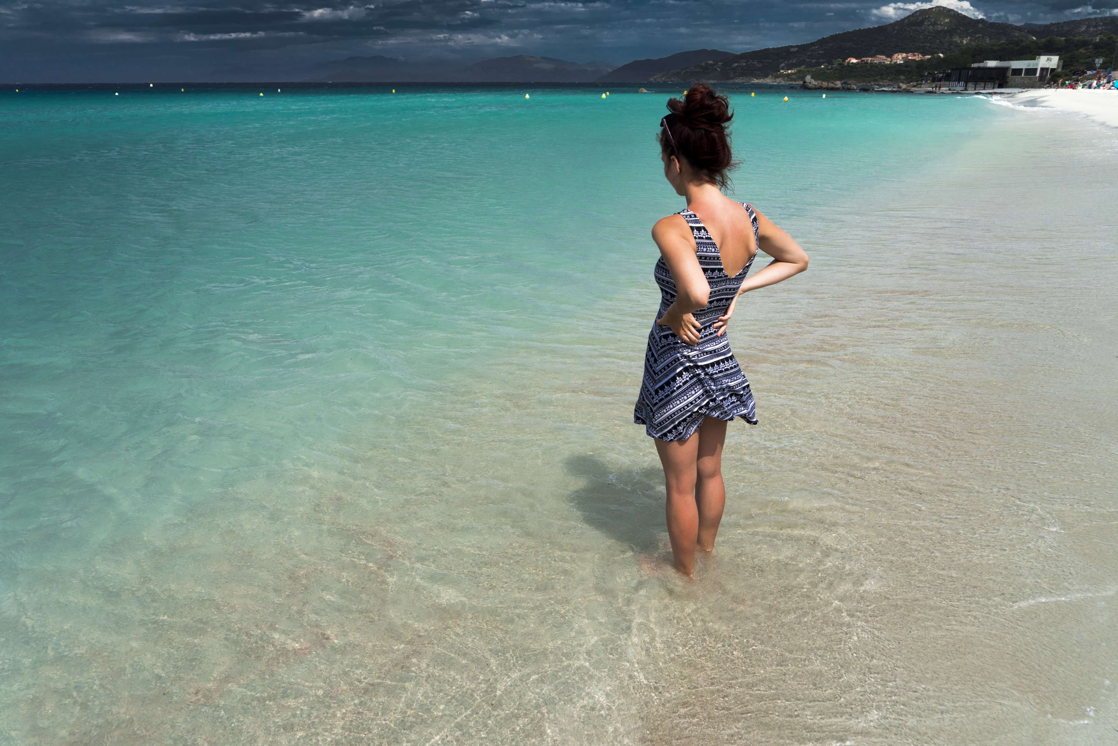 Woman in dress standing in the ocean at a beach HD Wallpaper