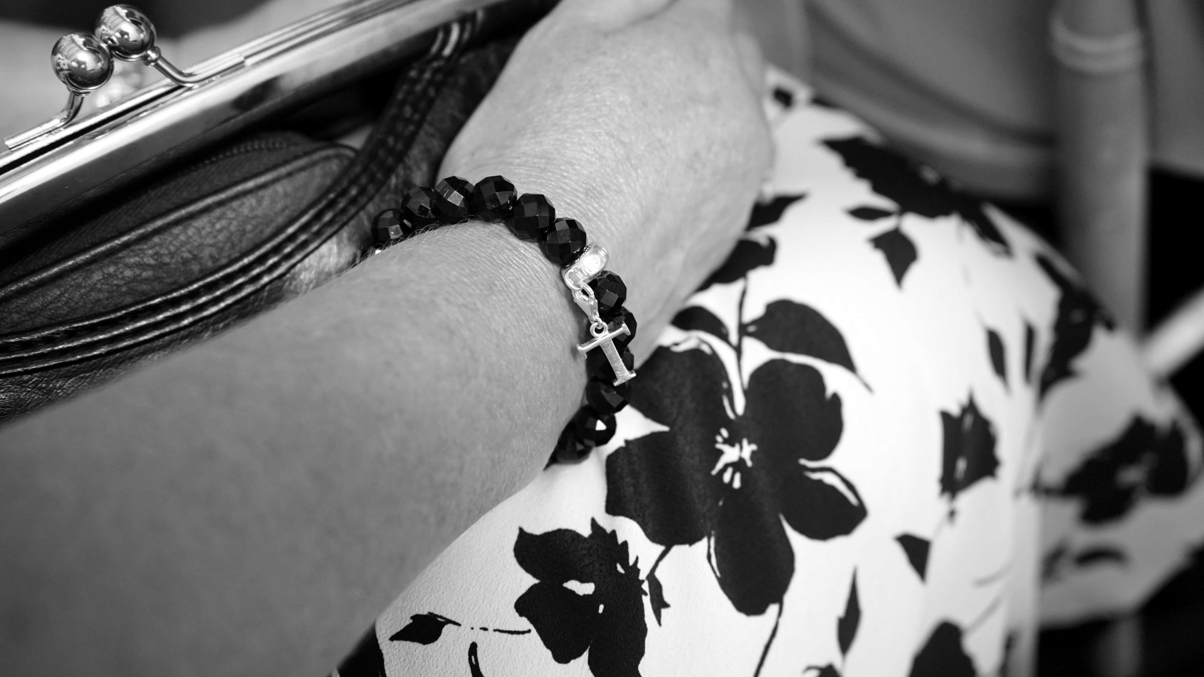 Woman wearing a black beaded bracelet with a cross charm HD Wallpaper