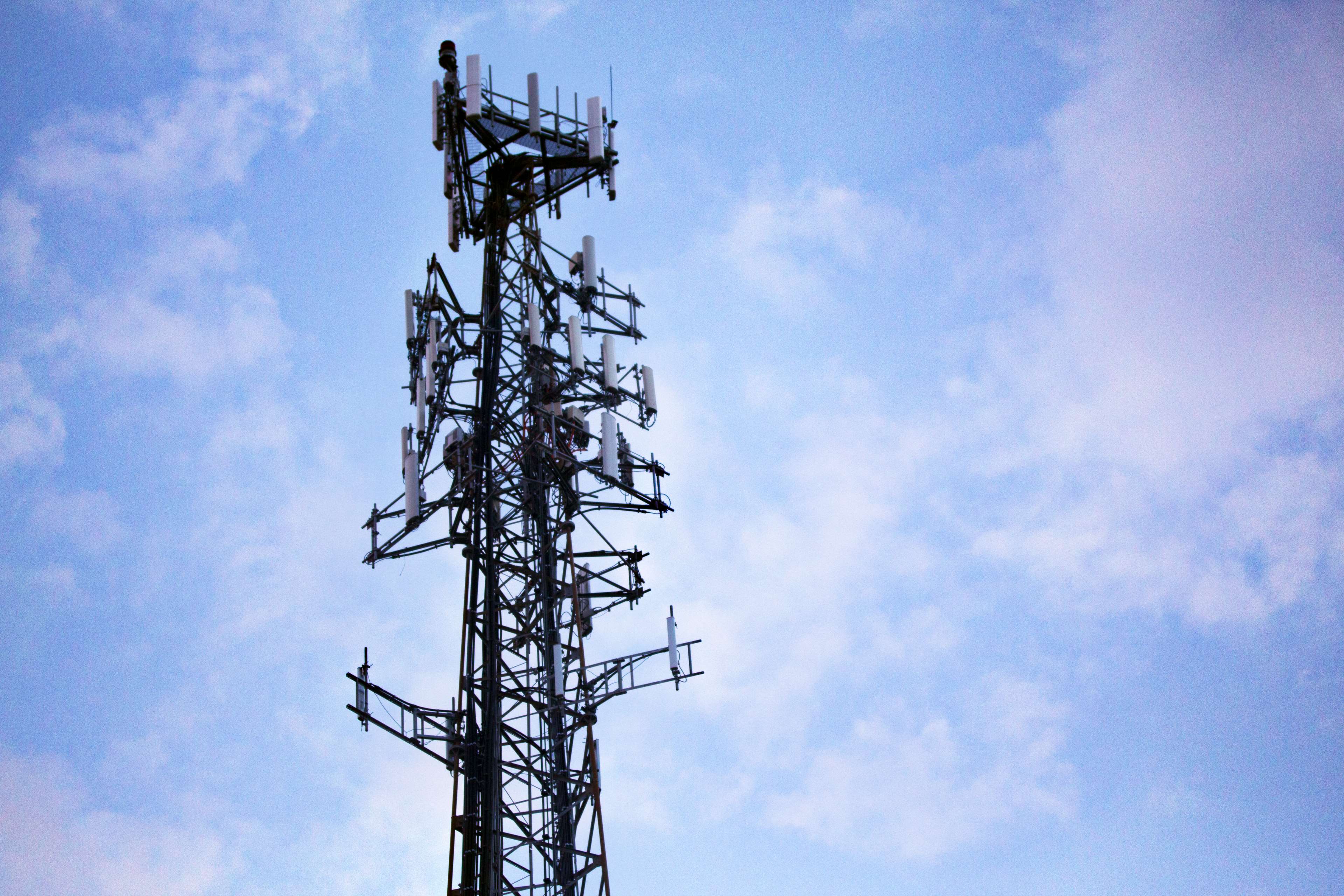 Cell tower with antennas against a cloudy sky HD Wallpaper