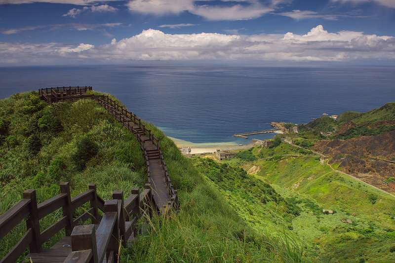 Wooden boardwalk on a green hill overlooking the ocean HD Wallpaper