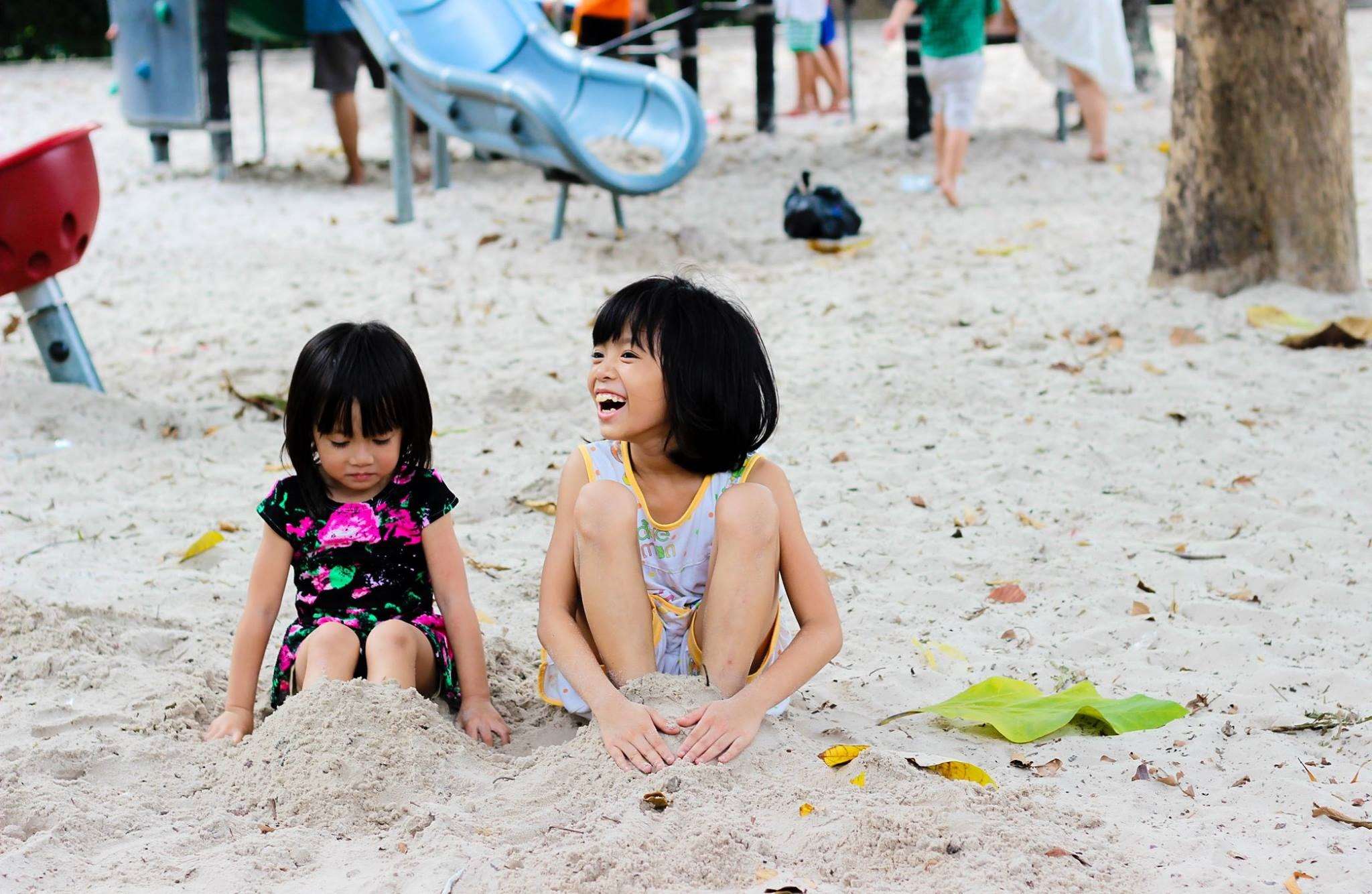 Two young girls playing in the sand at a playground HD Wallpaper
