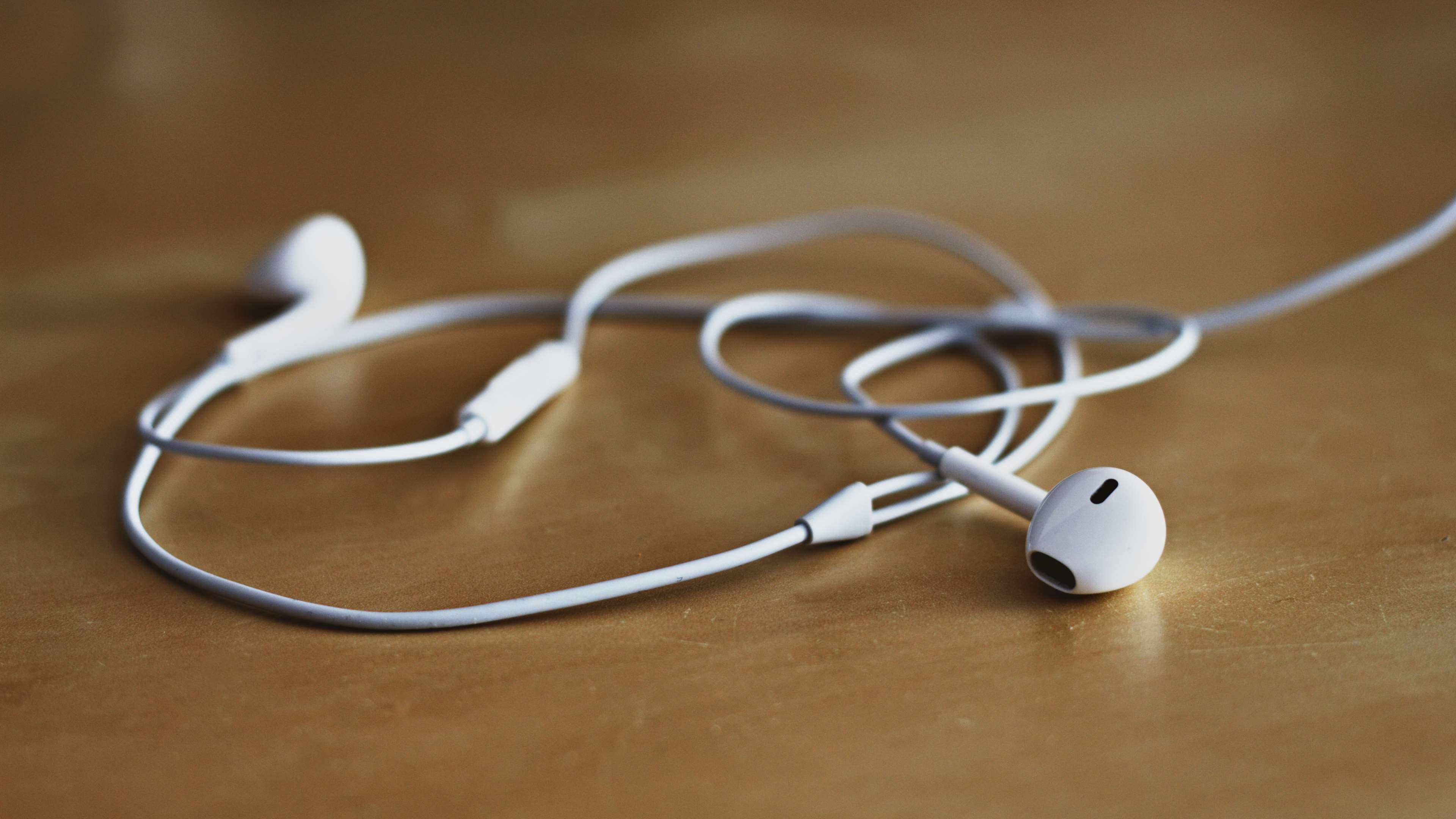 White Apple Earphones on a Wooden Table HD Wallpaper