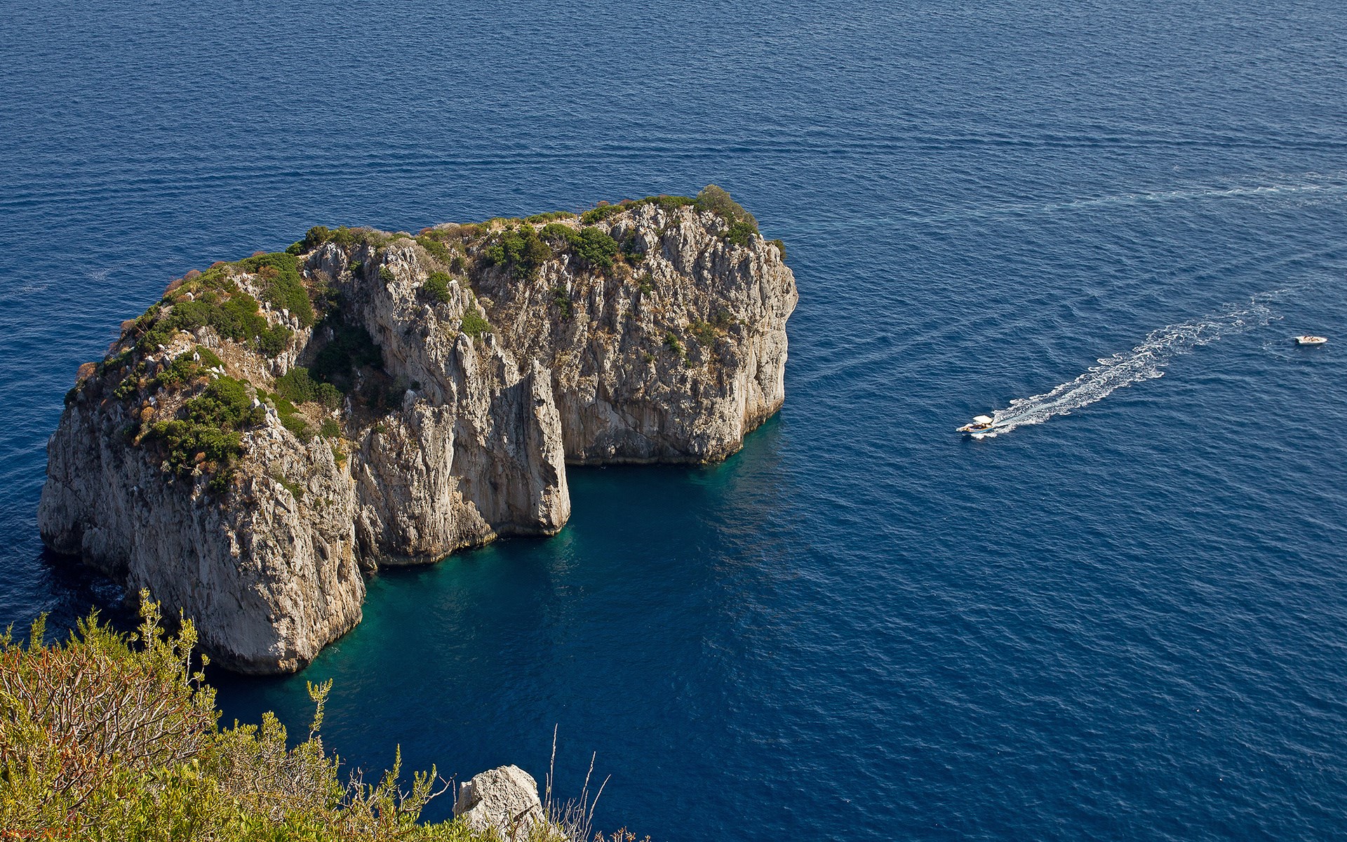 Rocky island with boats in blue sea HD Wallpaper