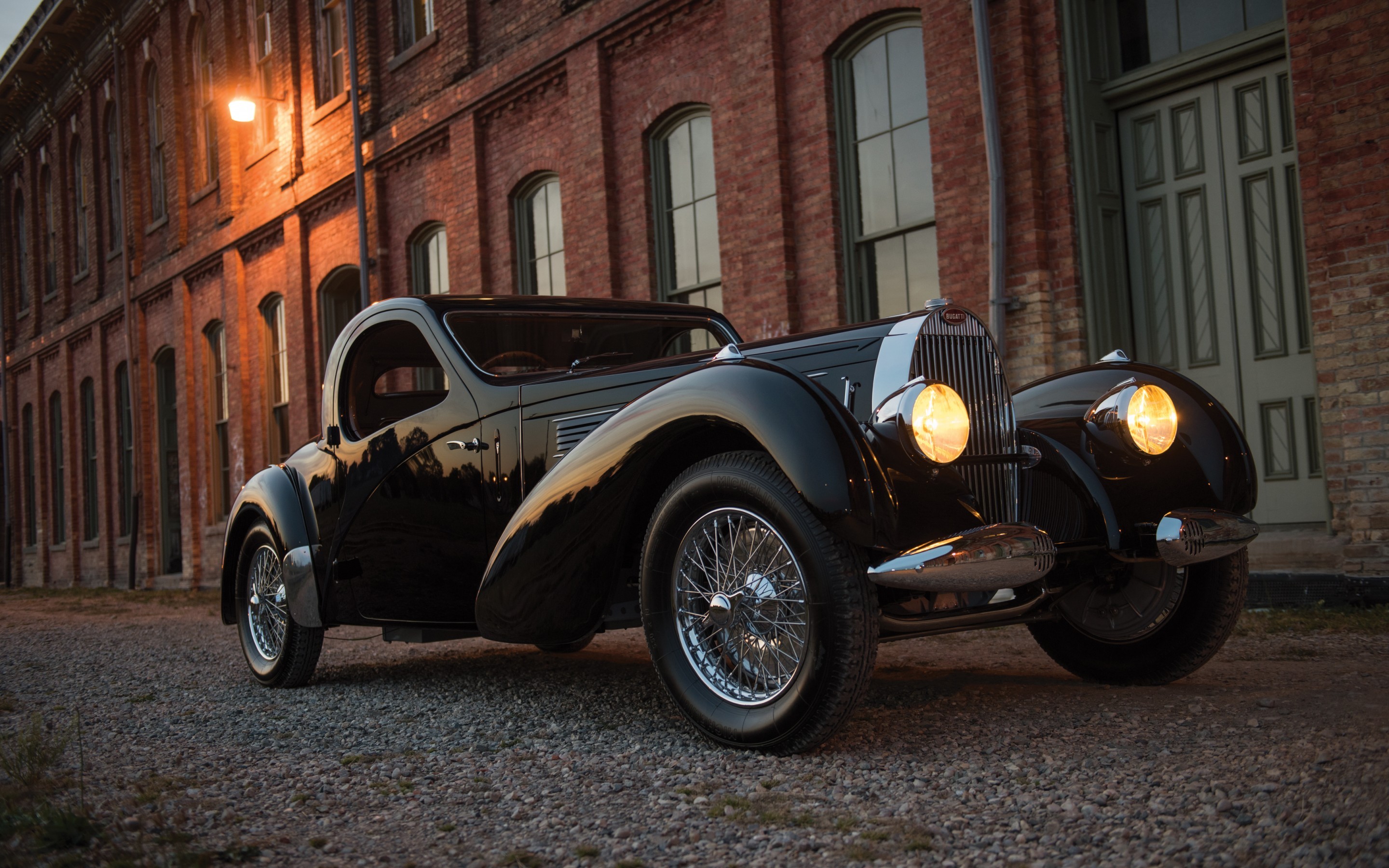 Vintage black Bugatti car parked outside brick building HD Wallpaper
