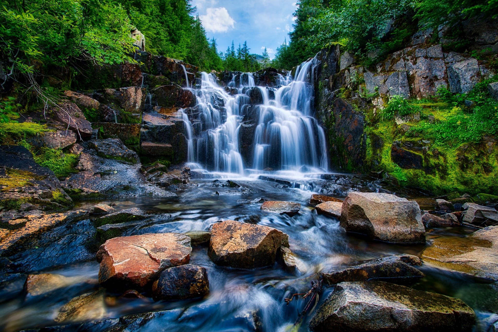 Waterfall cascading over rocks in a forest HD Wallpaper