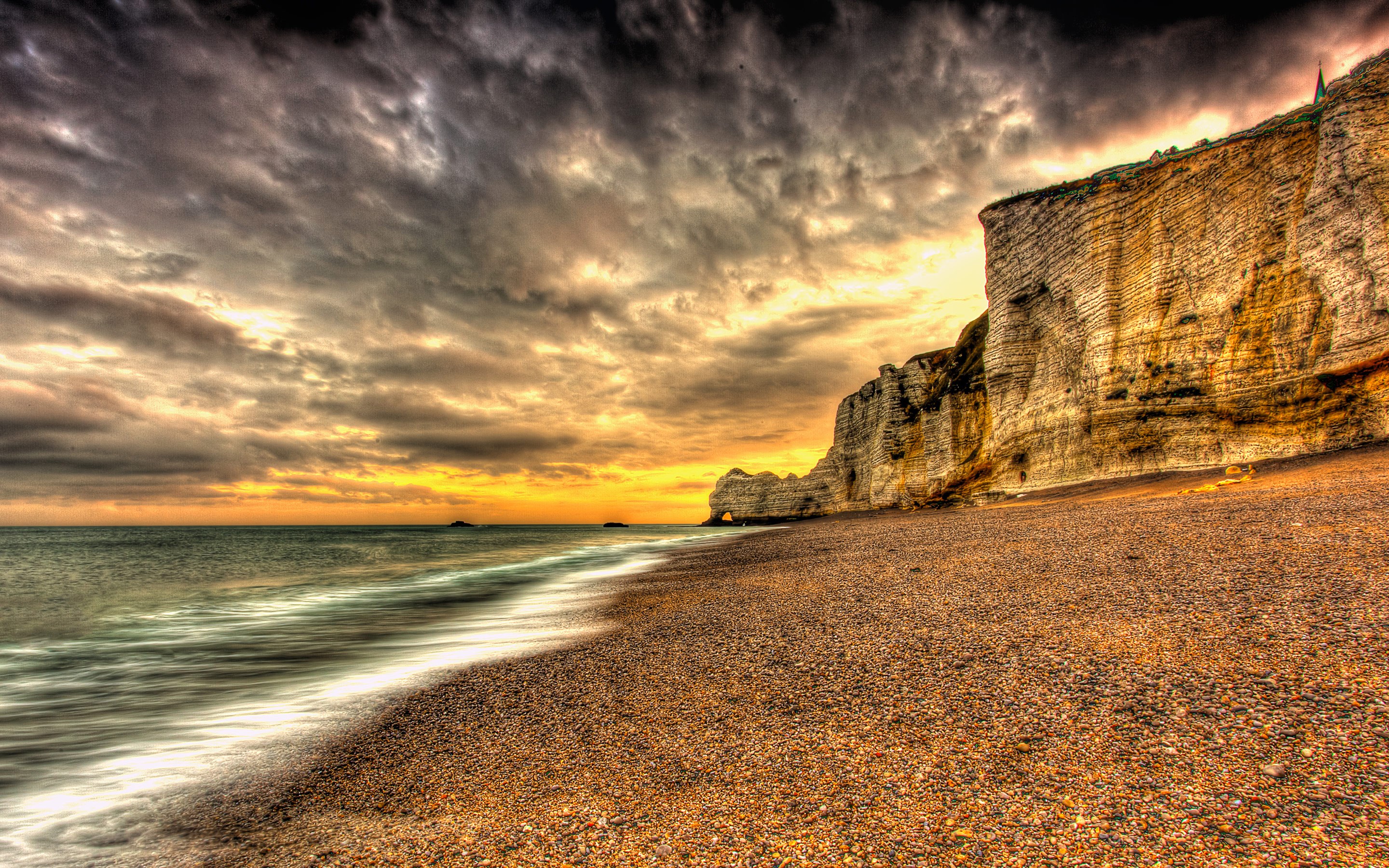 Dramatic sunset over a rocky beach and cliffs HD Wallpaper