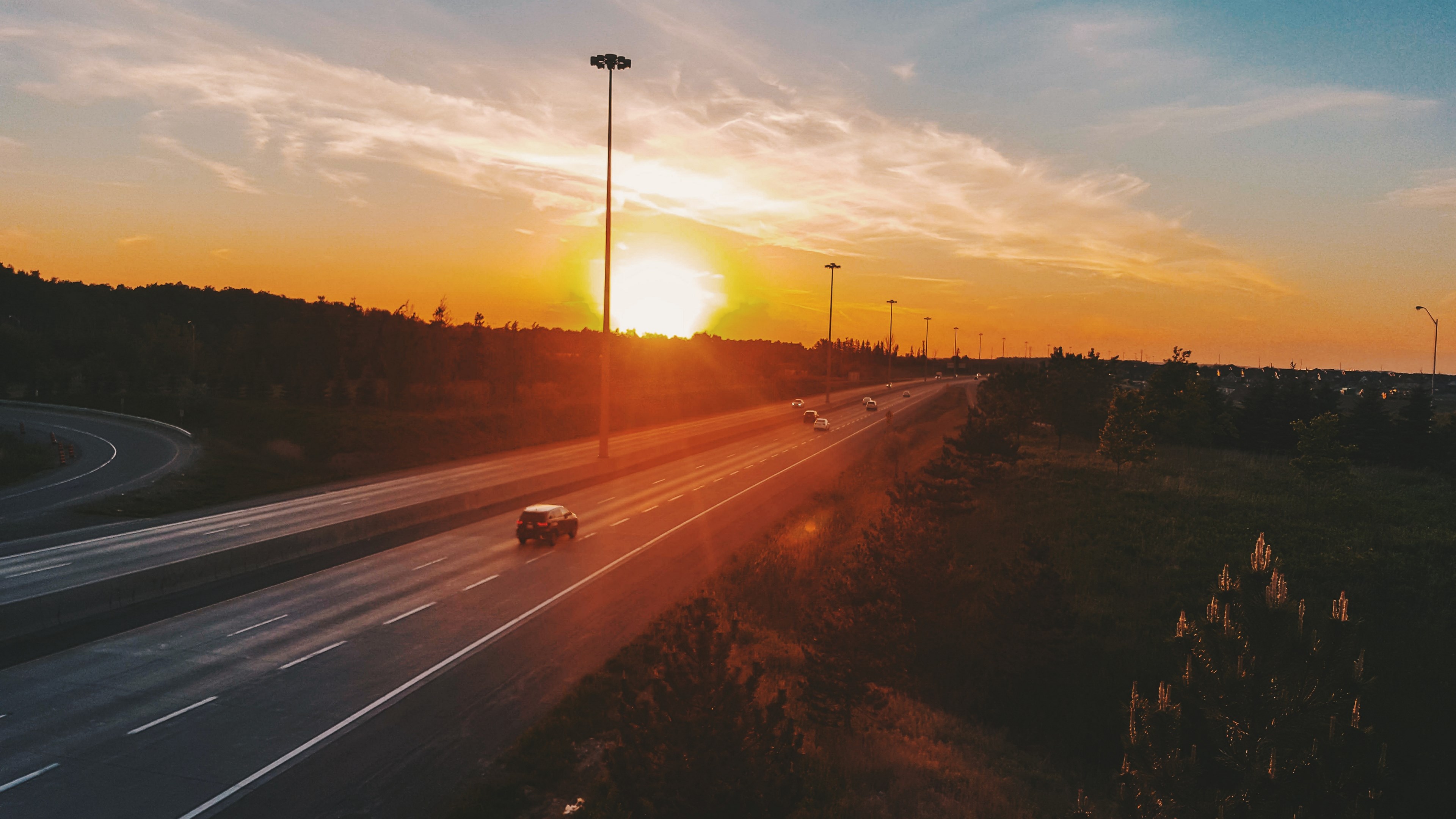 Highway at sunset with cars and streetlights HD Wallpaper