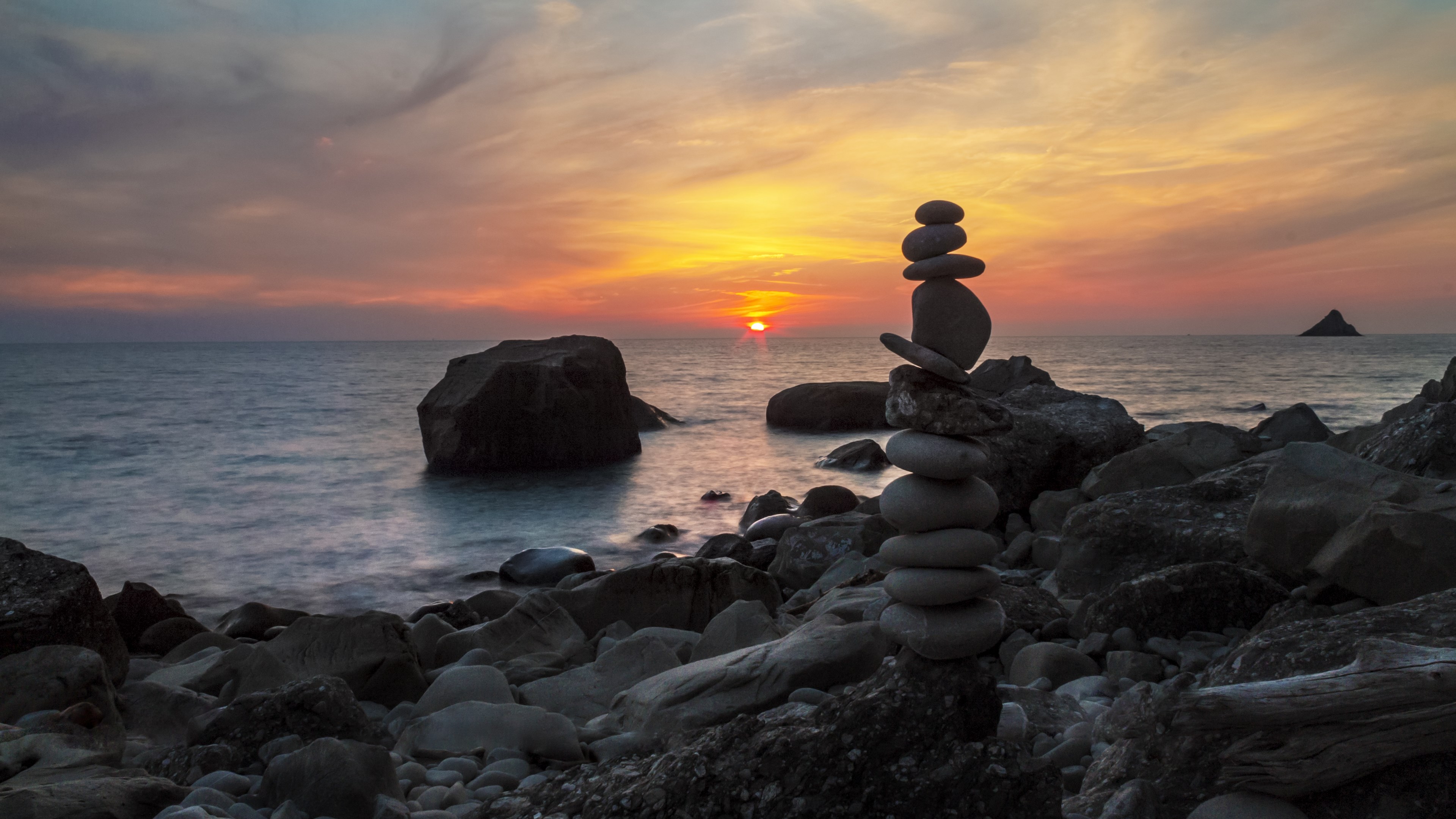 Stone cairn on a rocky beach at sunset HD Wallpaper