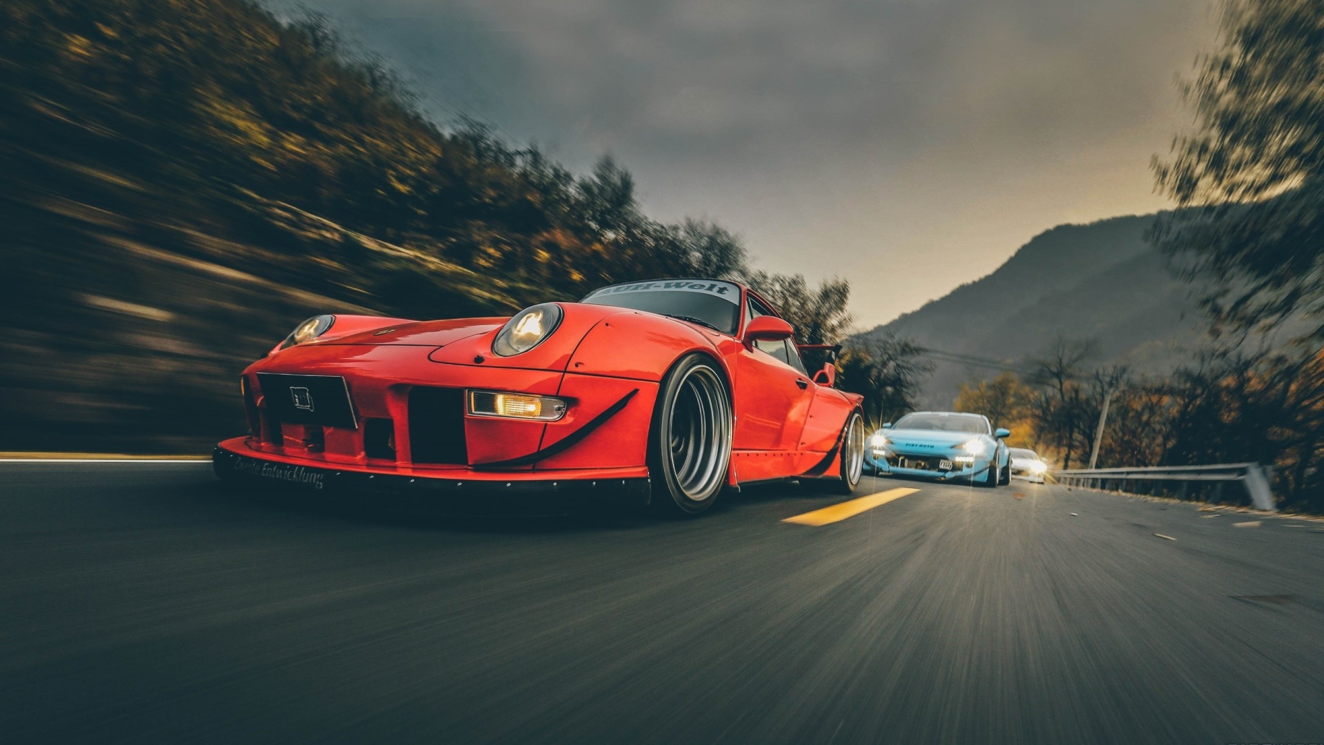 Red and blue Porsche 911s driving on a mountain road HD Wallpaper