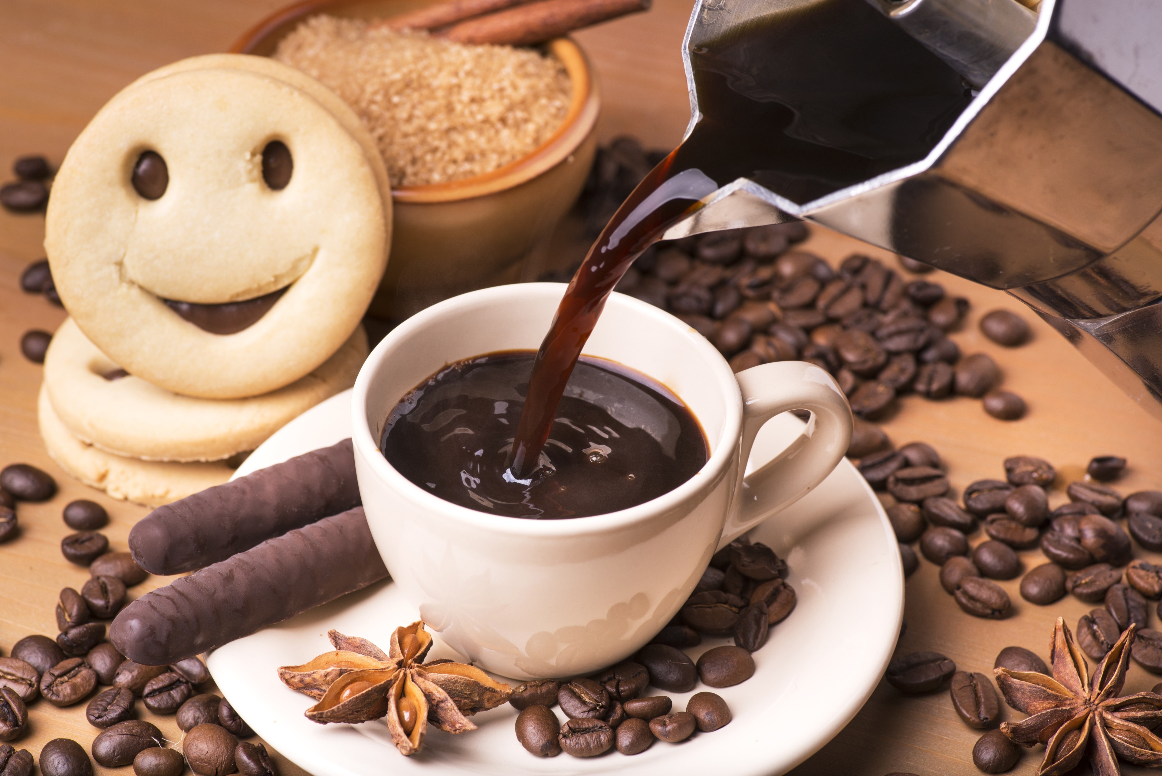 Coffee being poured into a cup with cookies and coffee beans HD Wallpaper