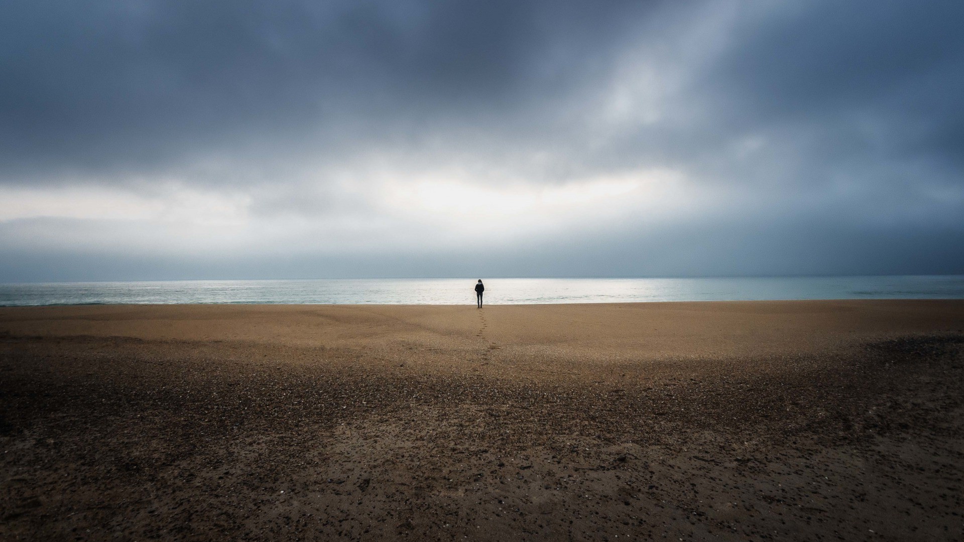 Person standing on a beach with stormy clouds HD Wallpaper