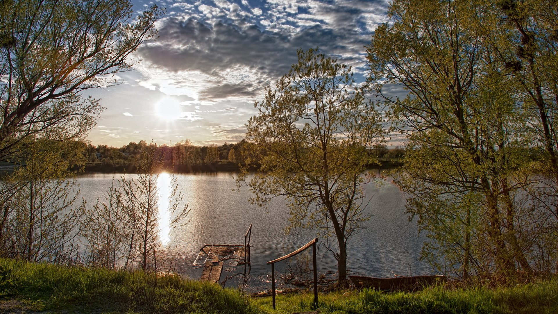 Sunset over a calm lake with trees and a small dock HD Wallpaper