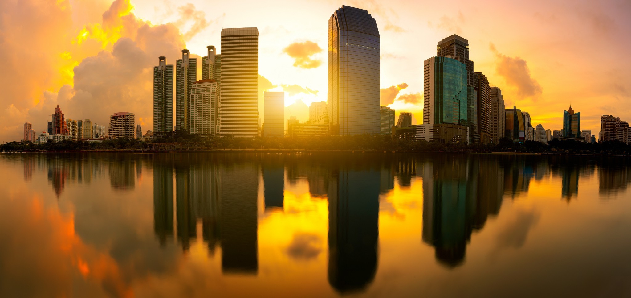 Cityscape with skyscrapers reflecting in water at sunset HD Wallpaper