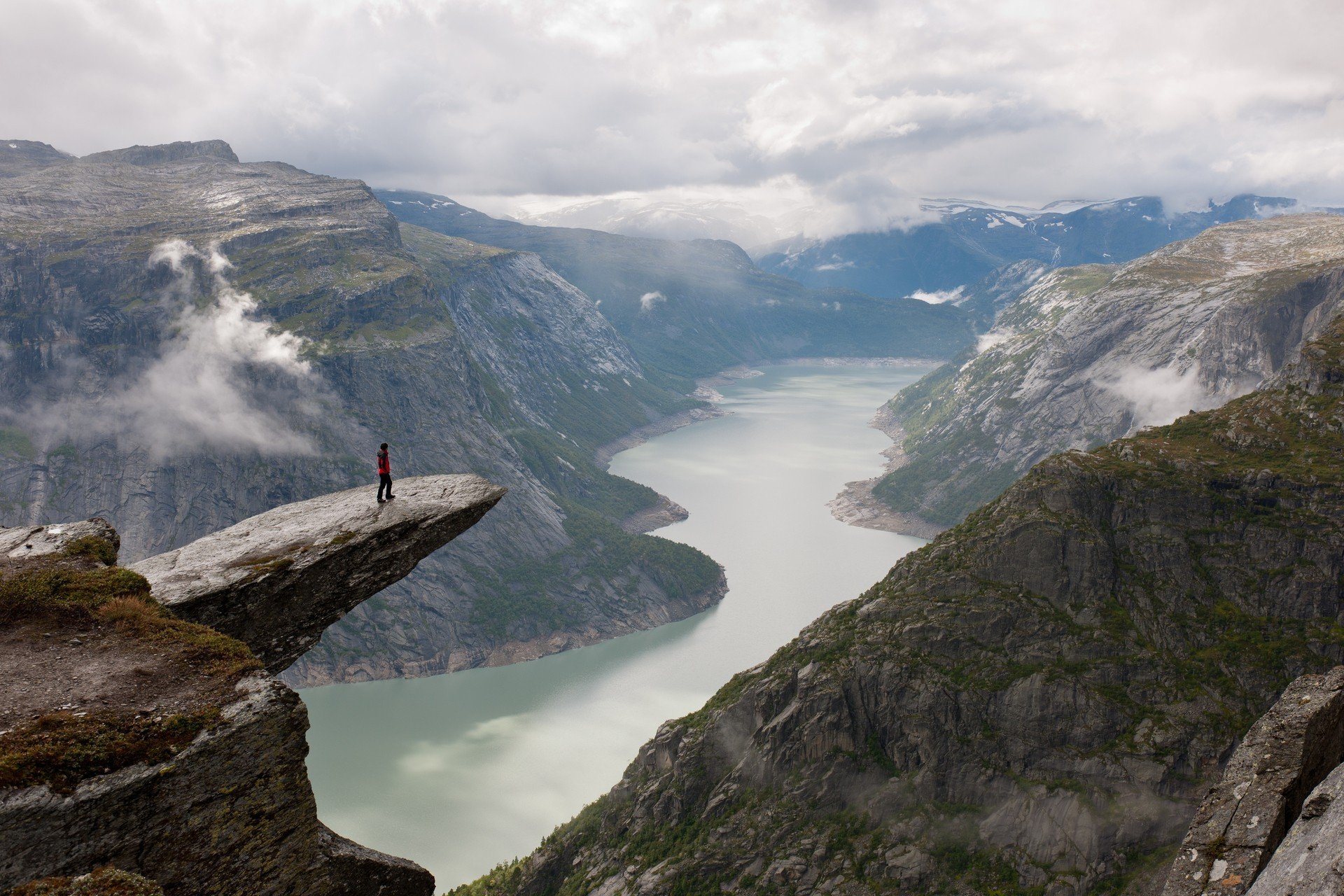 Person on Trolltunga cliff overlooking a fjord in Norway HD Wallpaper