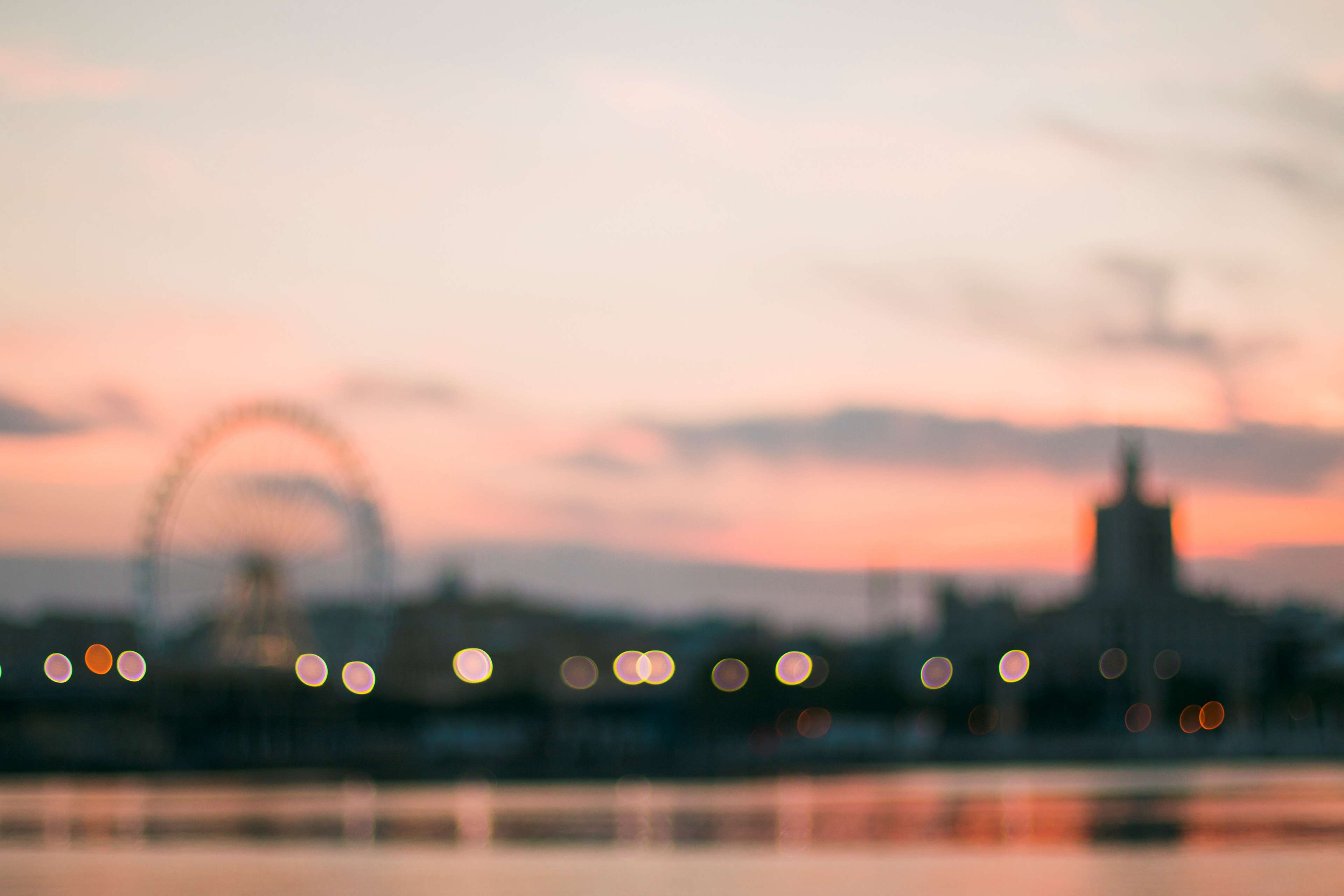 Bokeh lights over city skyline at sunset with Ferris wheel HD Wallpaper