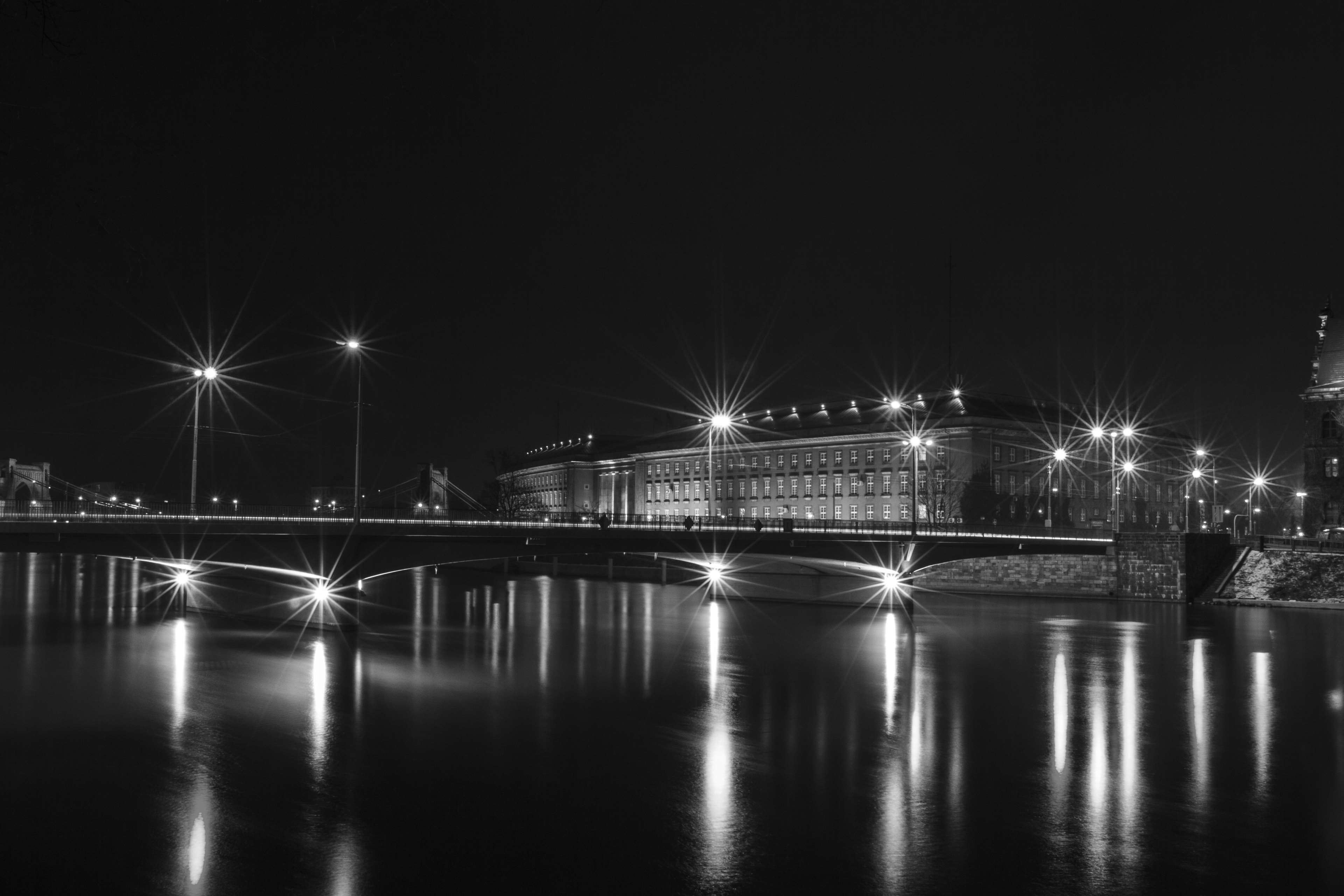 Bridge and building illuminated at night with water reflections HD Wallpaper