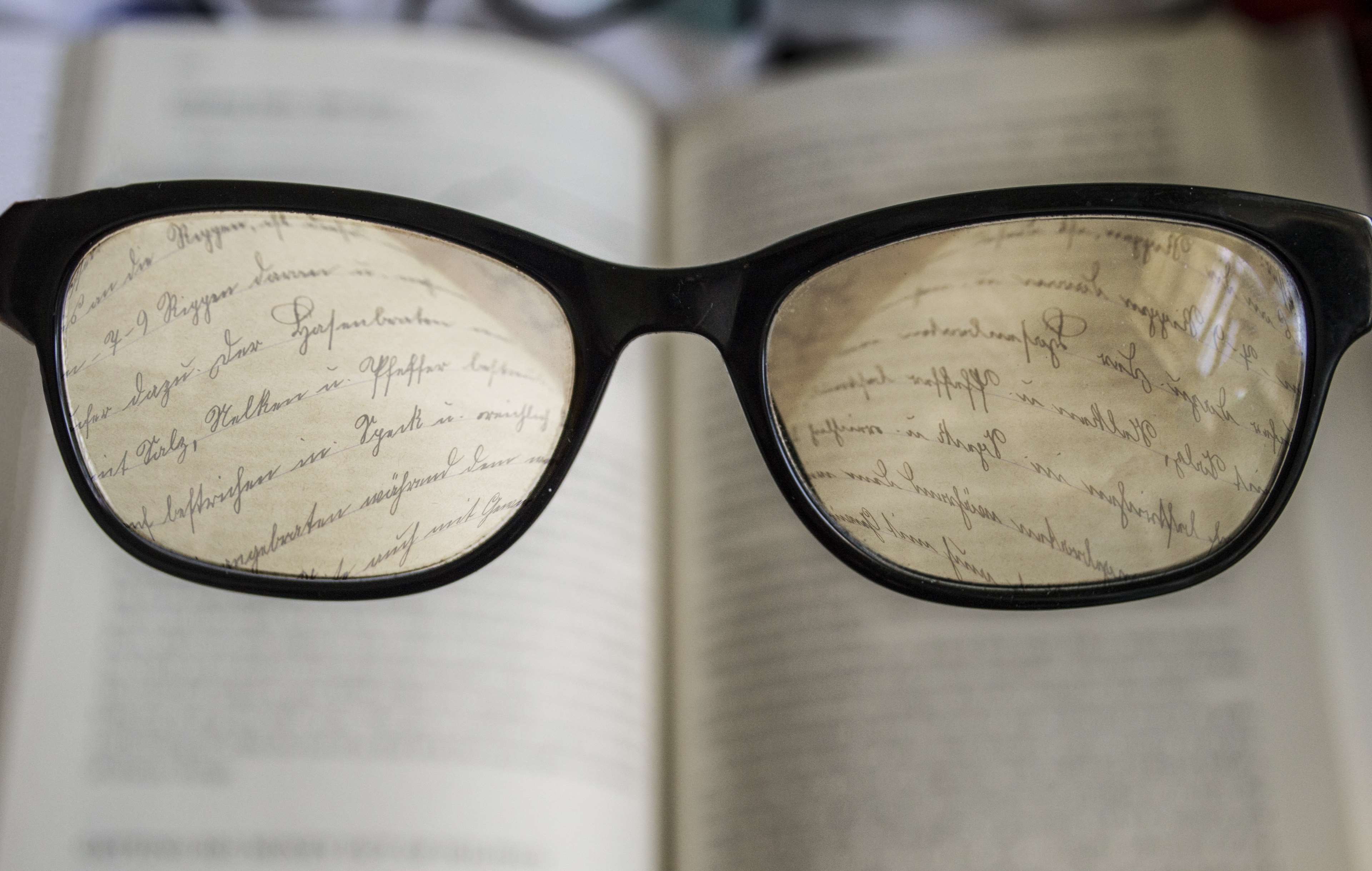 Glasses over an open book with handwritten text HD Wallpaper