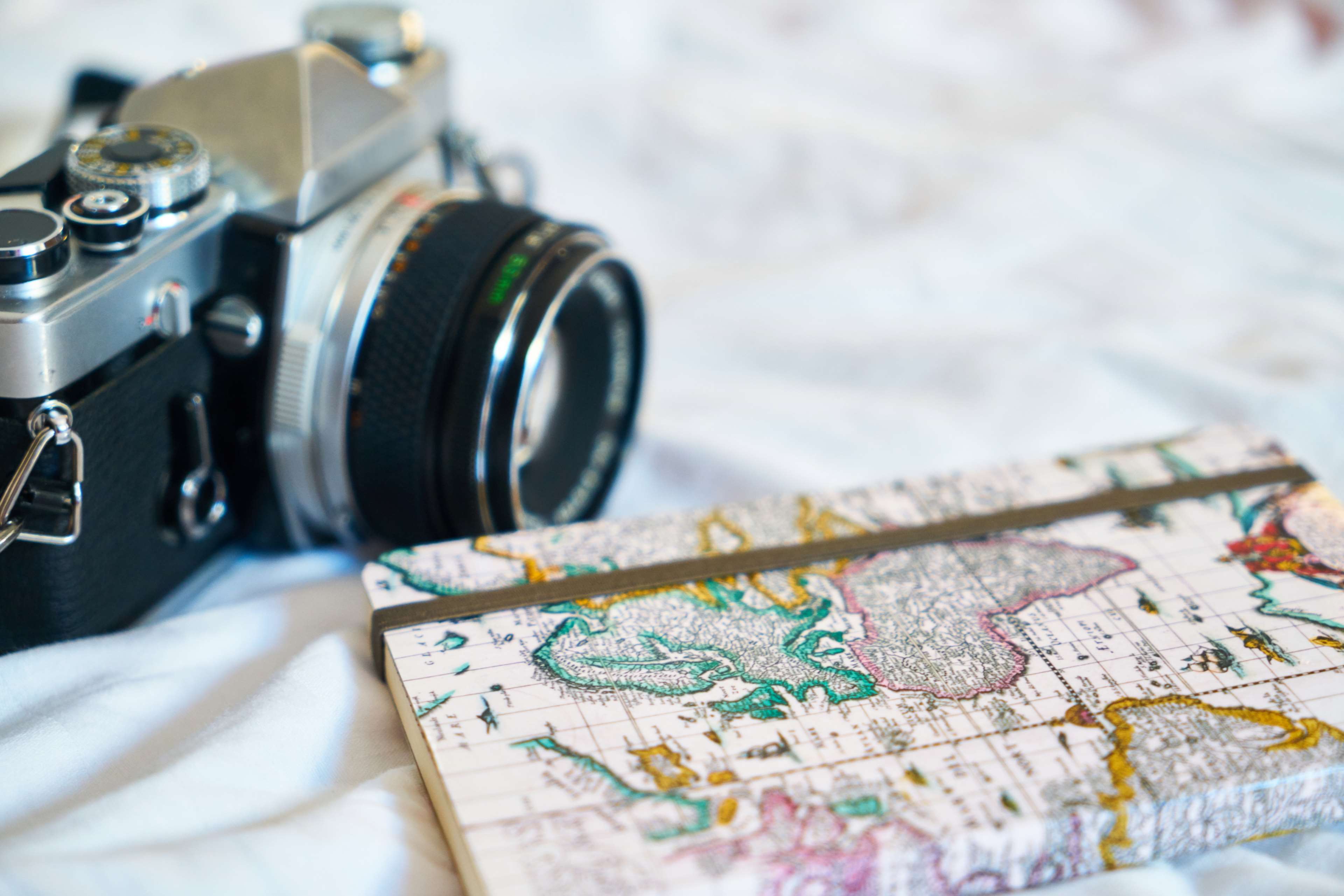 Vintage camera and map notebook on white fabric HD Wallpaper