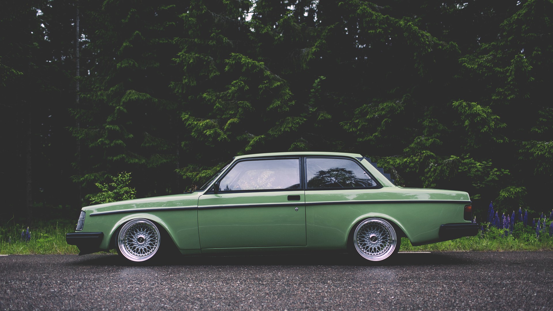 Green Volvo 242 parked by a forest HD Wallpaper