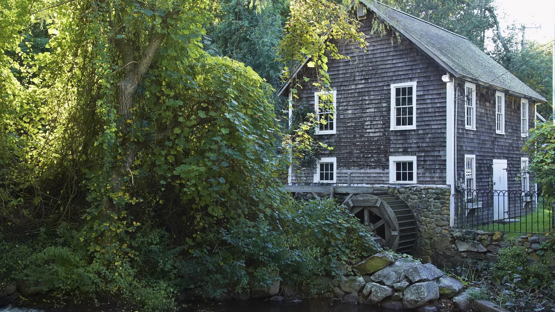 Old wooden mill with water wheel and surrounding greenery HD Wallpaper