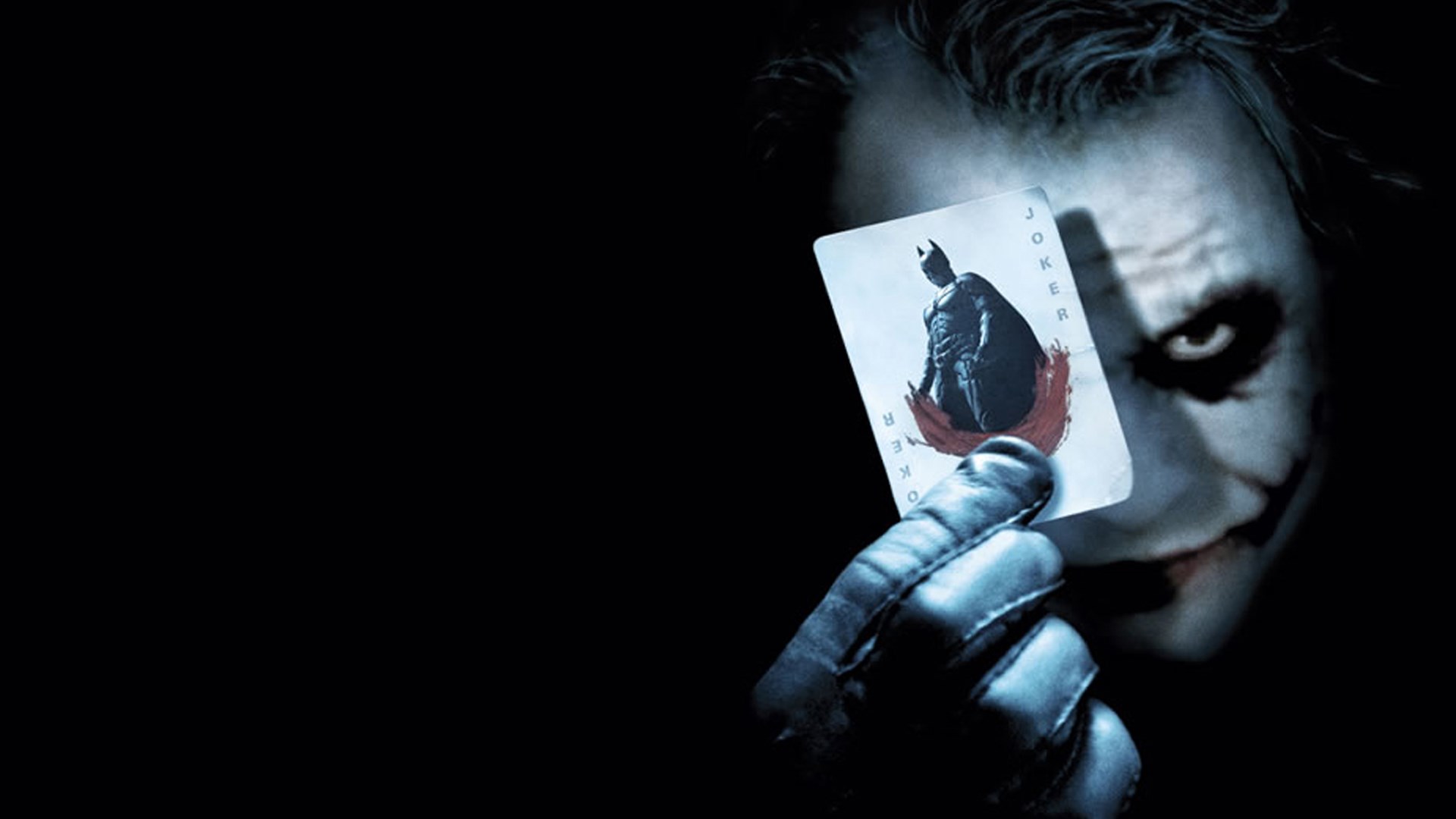 The Joker holding a Batman card HD Wallpaper