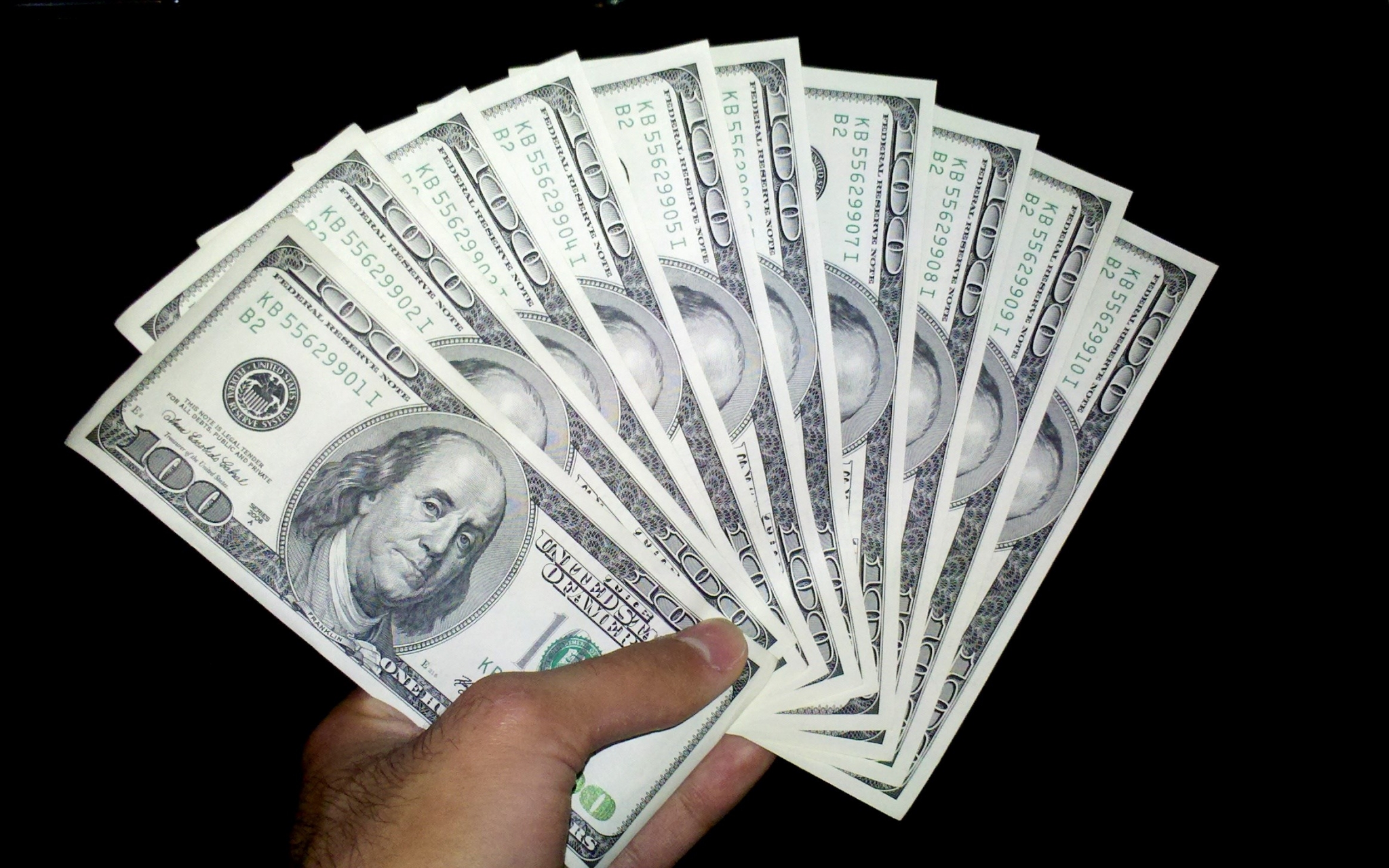 Hand holding fanned US 100 dollar bills HD Wallpaper