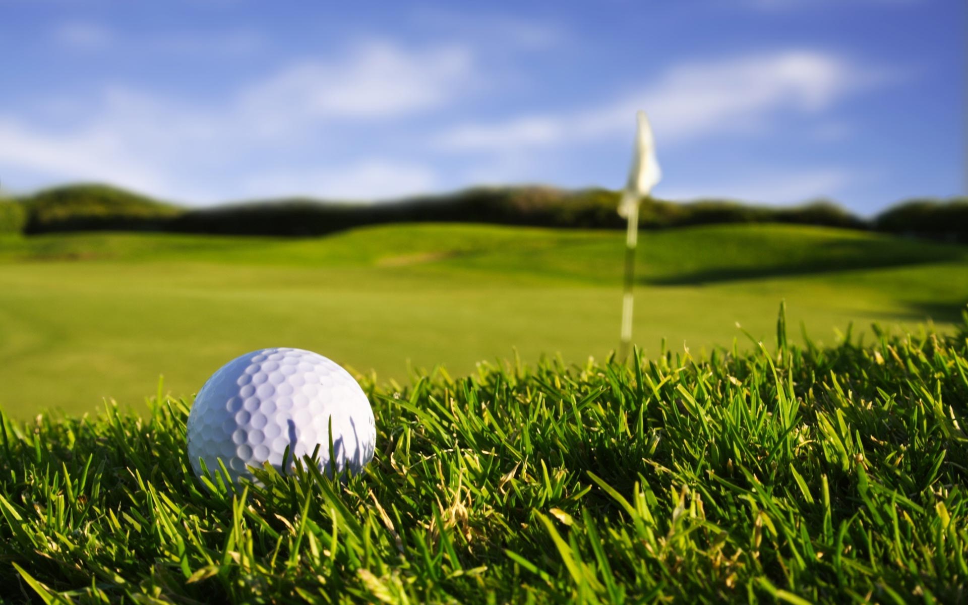 Golf ball on a golf course with a flag HD Wallpaper