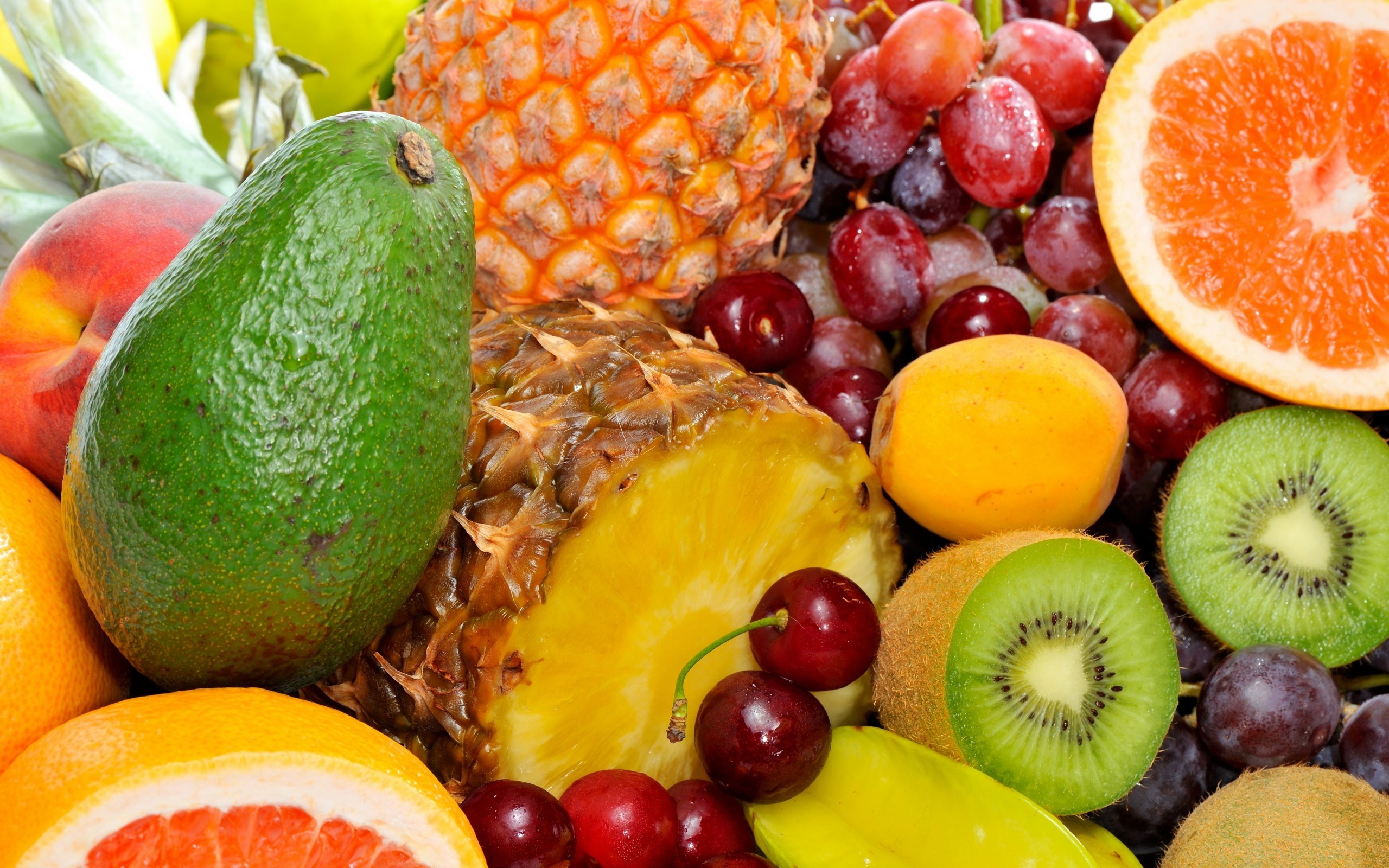 A vibrant assortment of fresh fruits including pineapple, avocado, grapes, kiwi, and grapefruit. HD Wallpaper